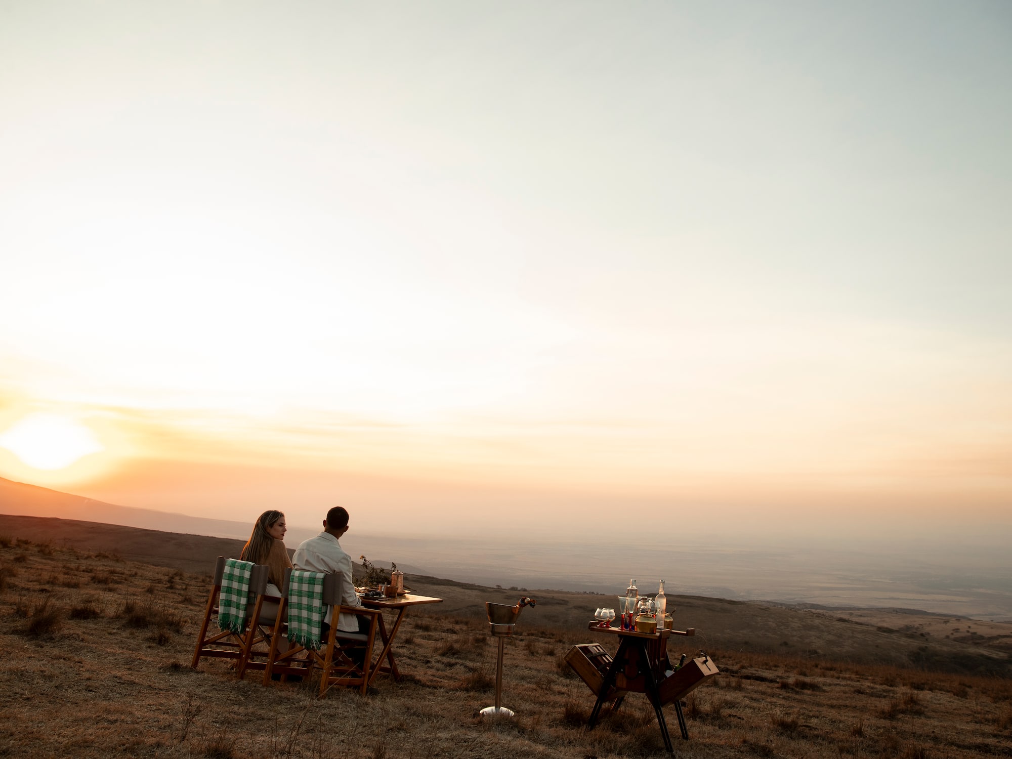 a man and woman sitting at a table in a field