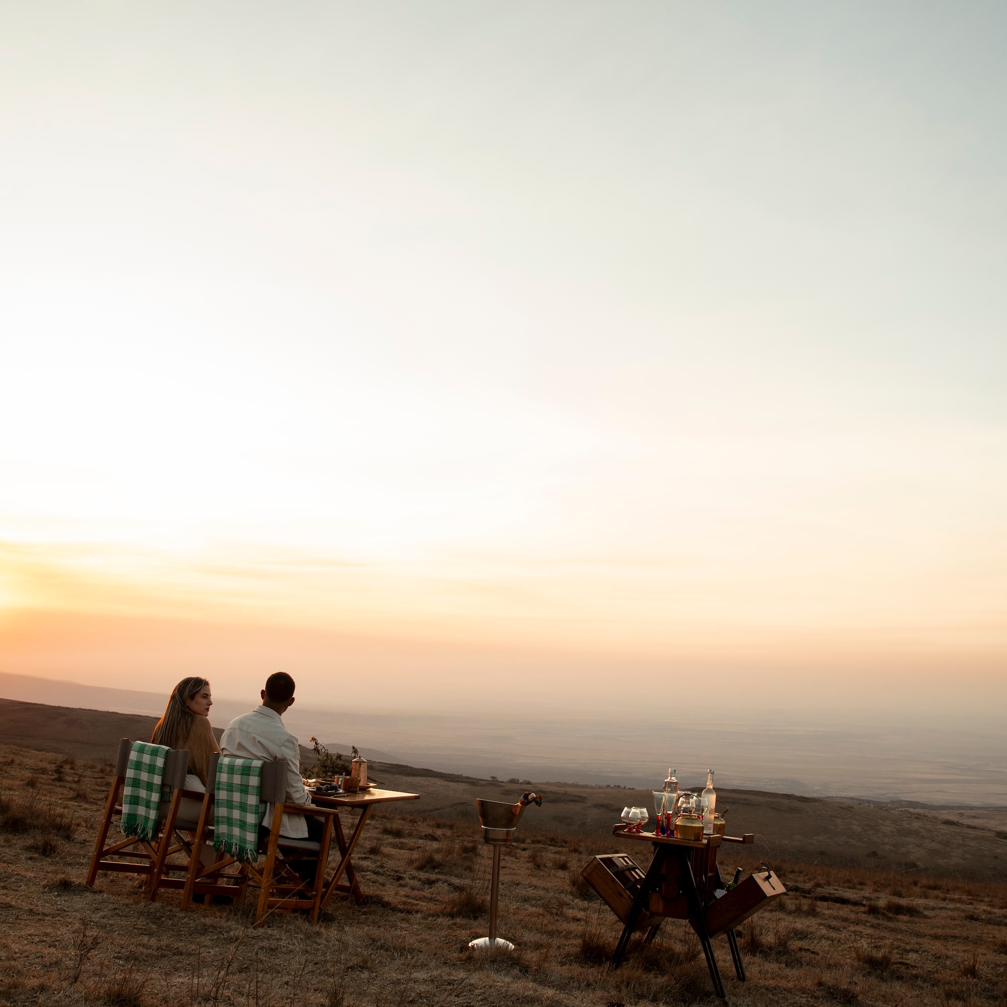 a man and woman sitting at a table in a field