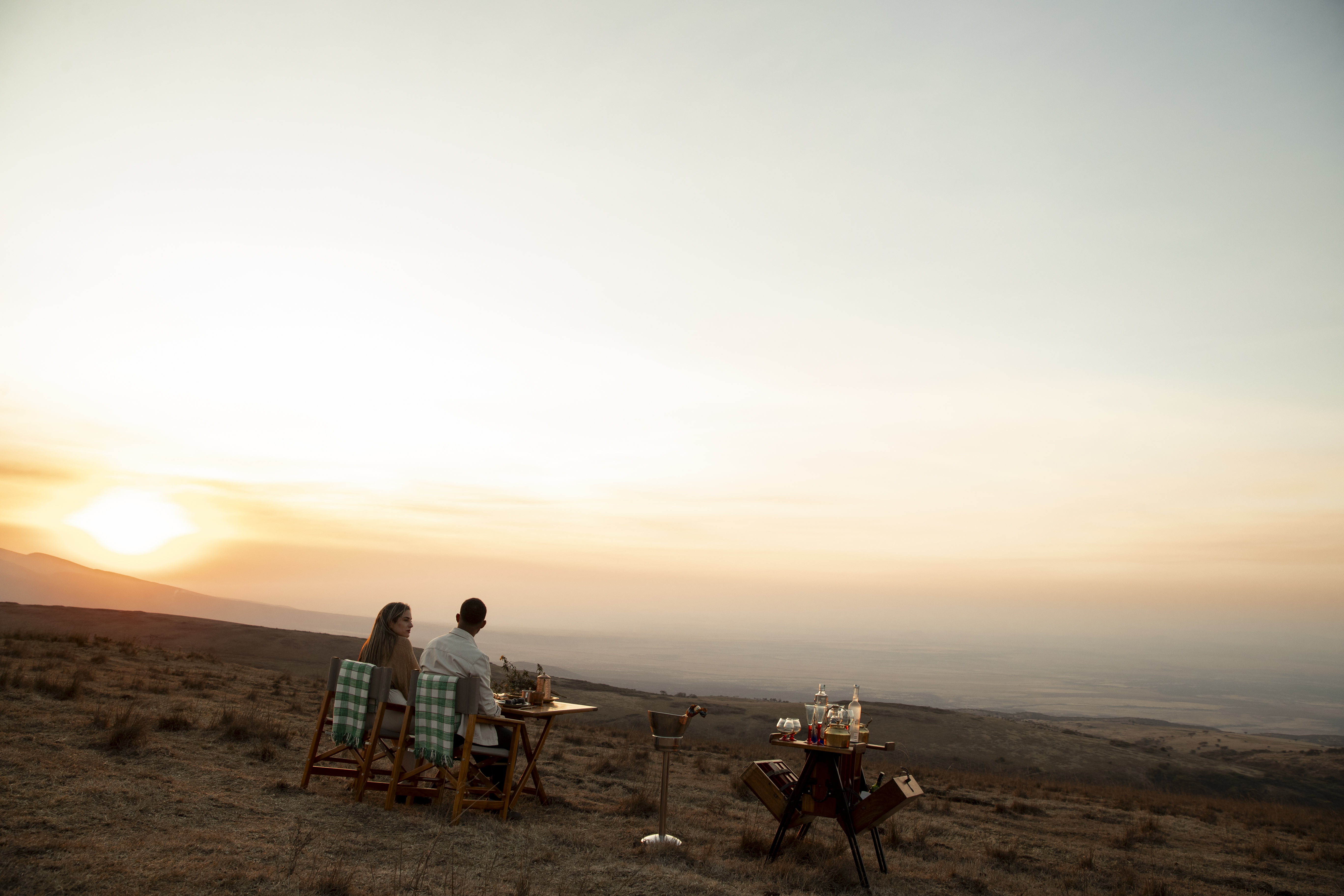 Cena romántica de pareja en la montaña al atardecer, paisaje africano.