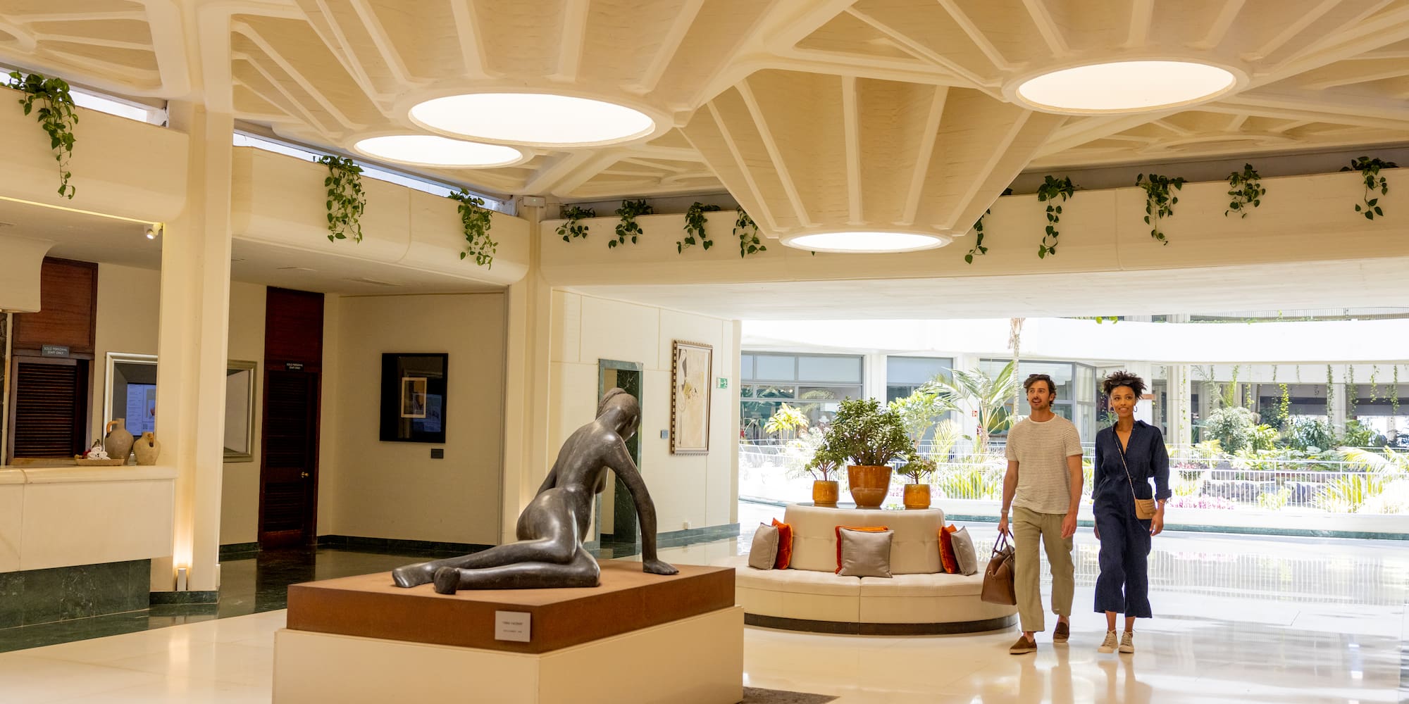 a man and woman standing in a room with a statue