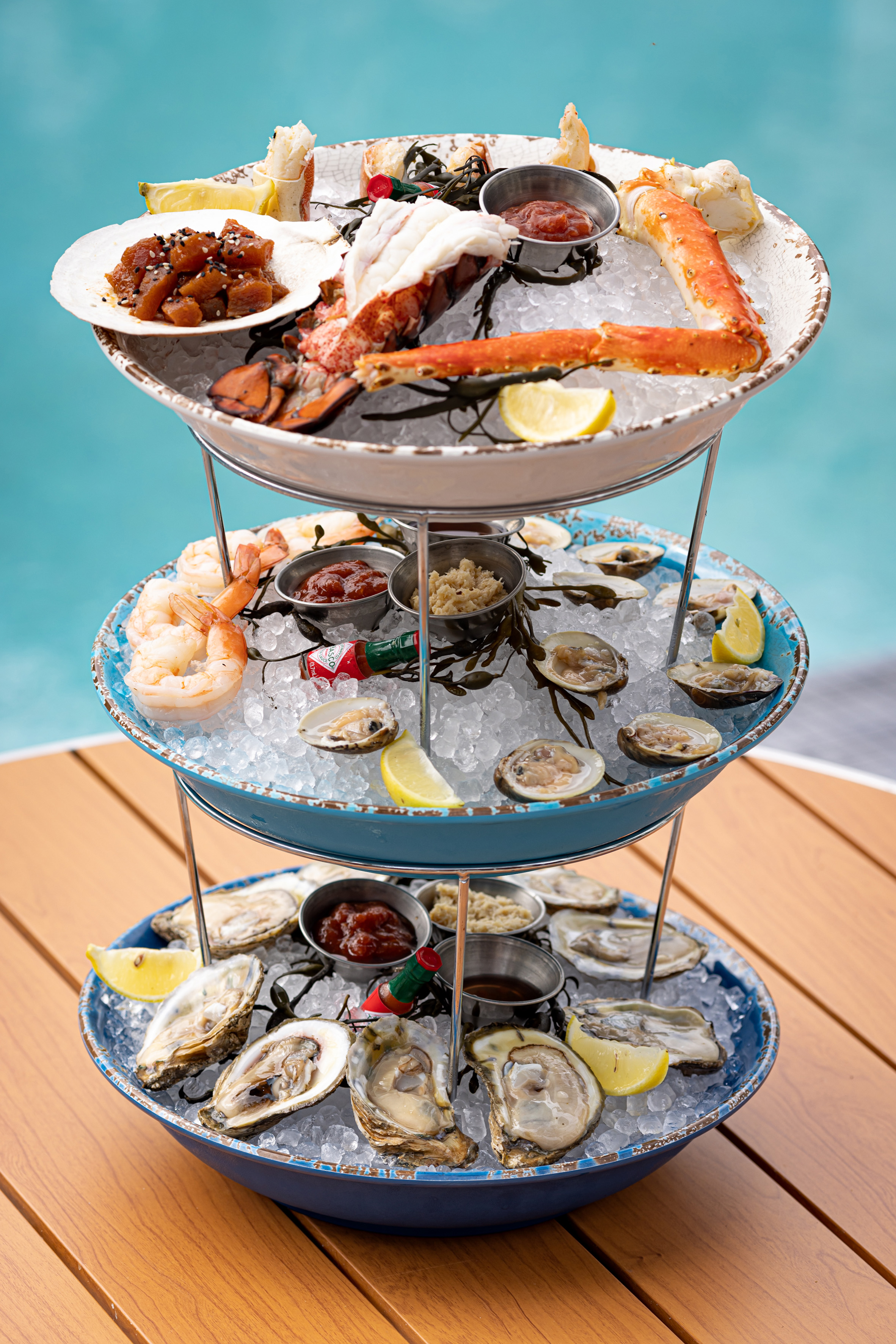 Fresh seafood tower with lobster, king crab, shrimp, oysters, and clams by pool.