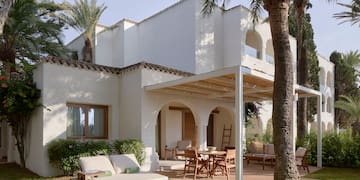 a patio area with chairs and tables in front of a white building