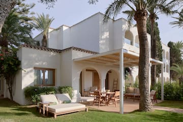 a patio area with chairs and tables in front of a white building