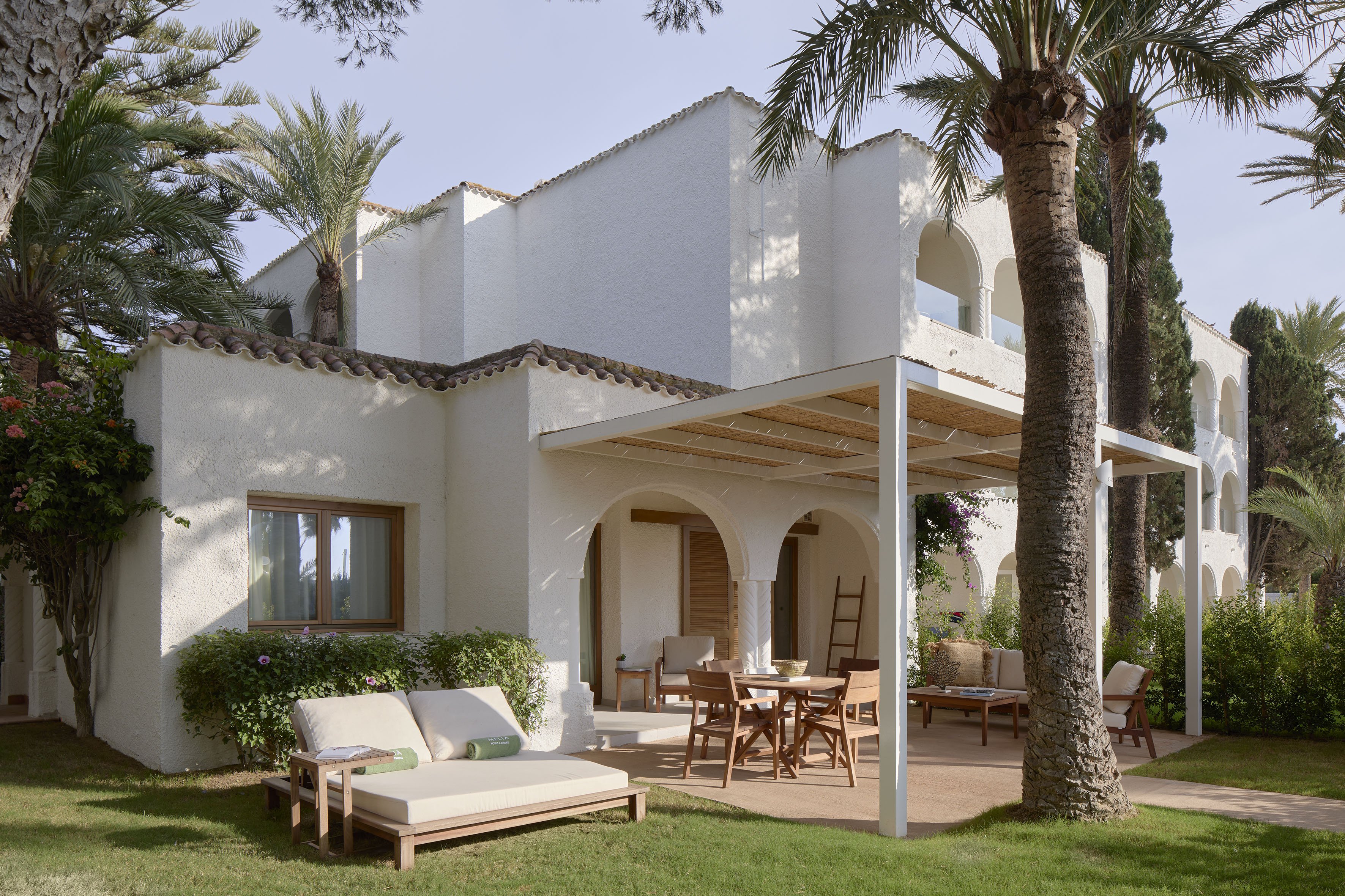 a patio area with chairs and tables in front of a white building