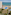 Oceanfront hotel resort with large pool, sandy beach, palm trees, and tennis court.