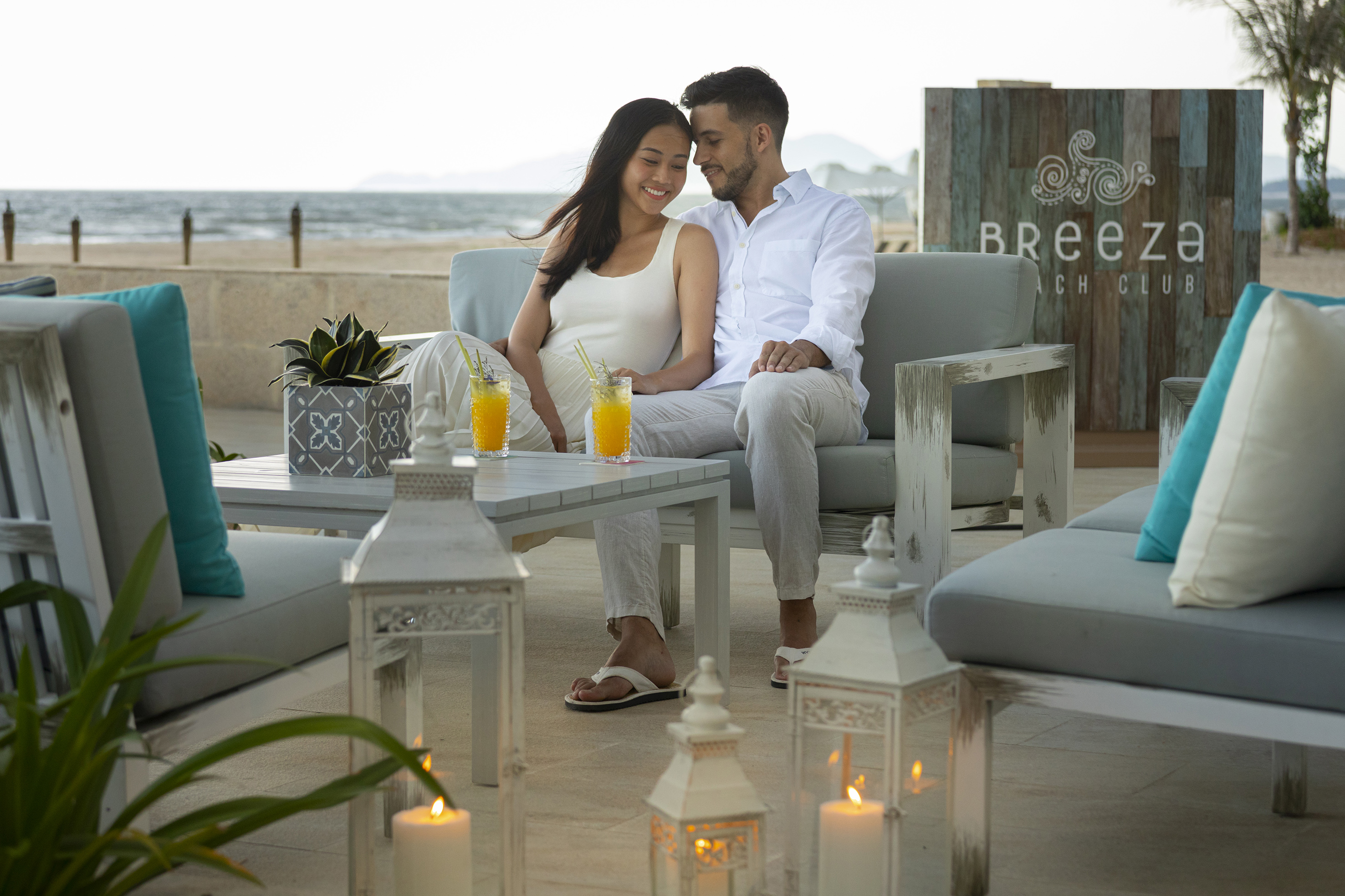Couple enjoying cocktails at Breeza Beach Club lounge overlooking the ocean.