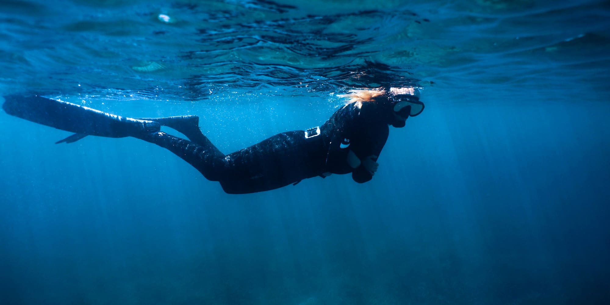 a woman in a black wetsuit and snorkeling gear underwater