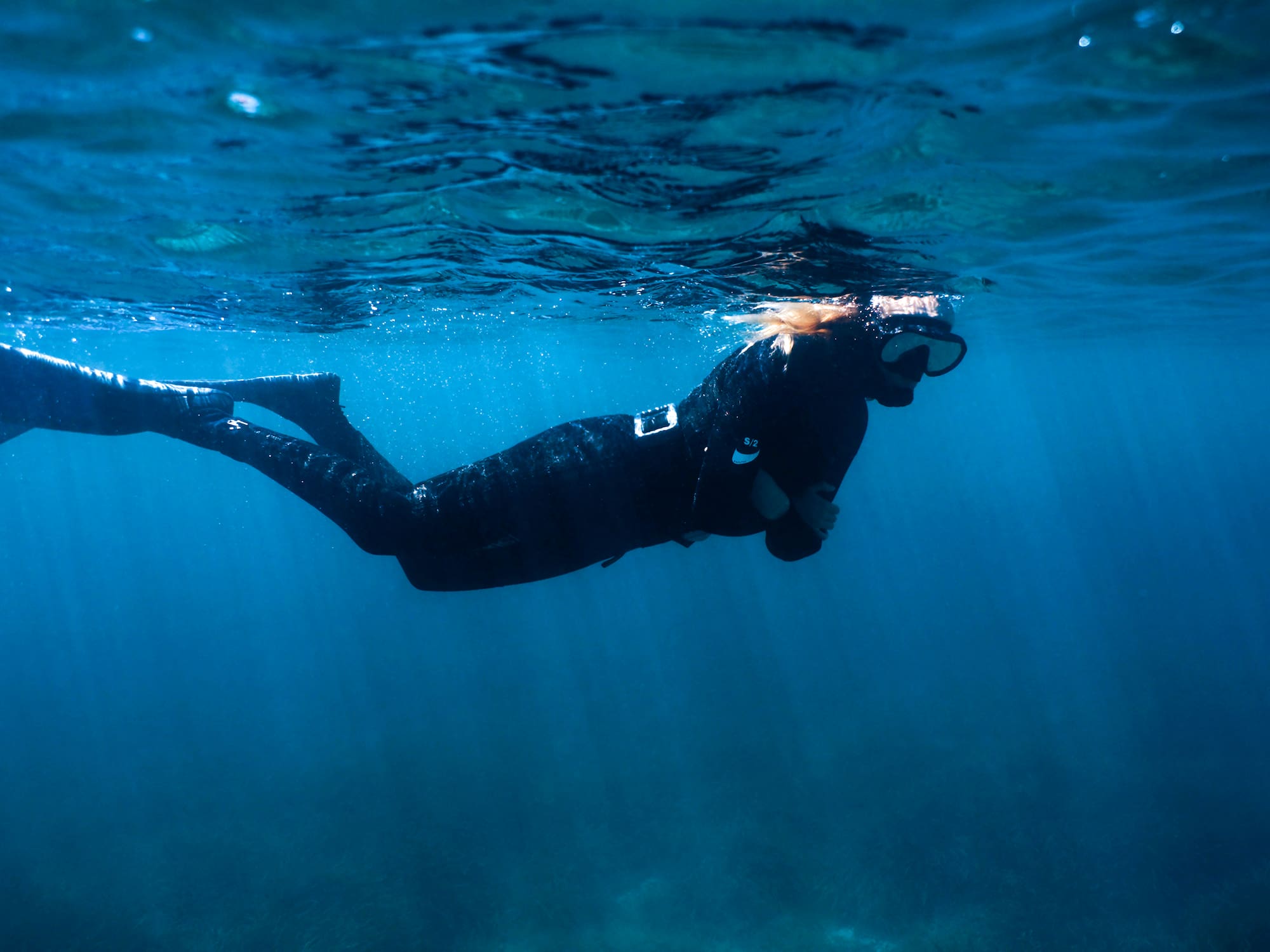 a woman in a black wetsuit and snorkeling gear underwater