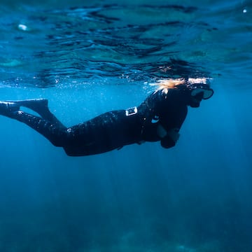a woman in a black wetsuit and snorkeling gear underwater