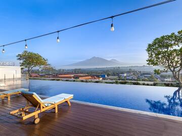 a pool with a deck chair and a mountain in the background