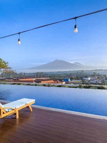 a pool with a deck chair and a mountain in the background