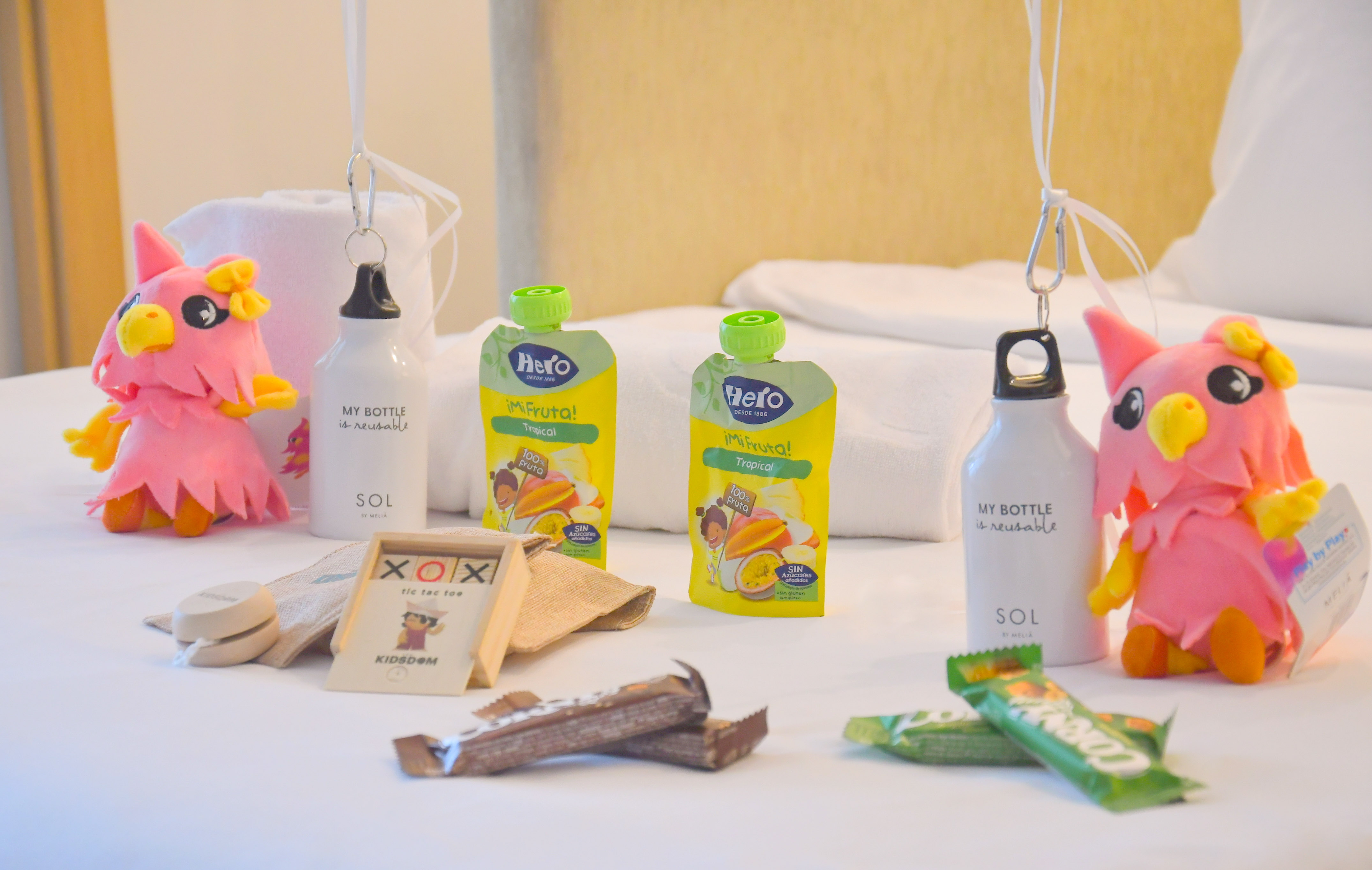 Hotel kids' welcome kit with plush toys, reusable bottles, and fruit pouches.