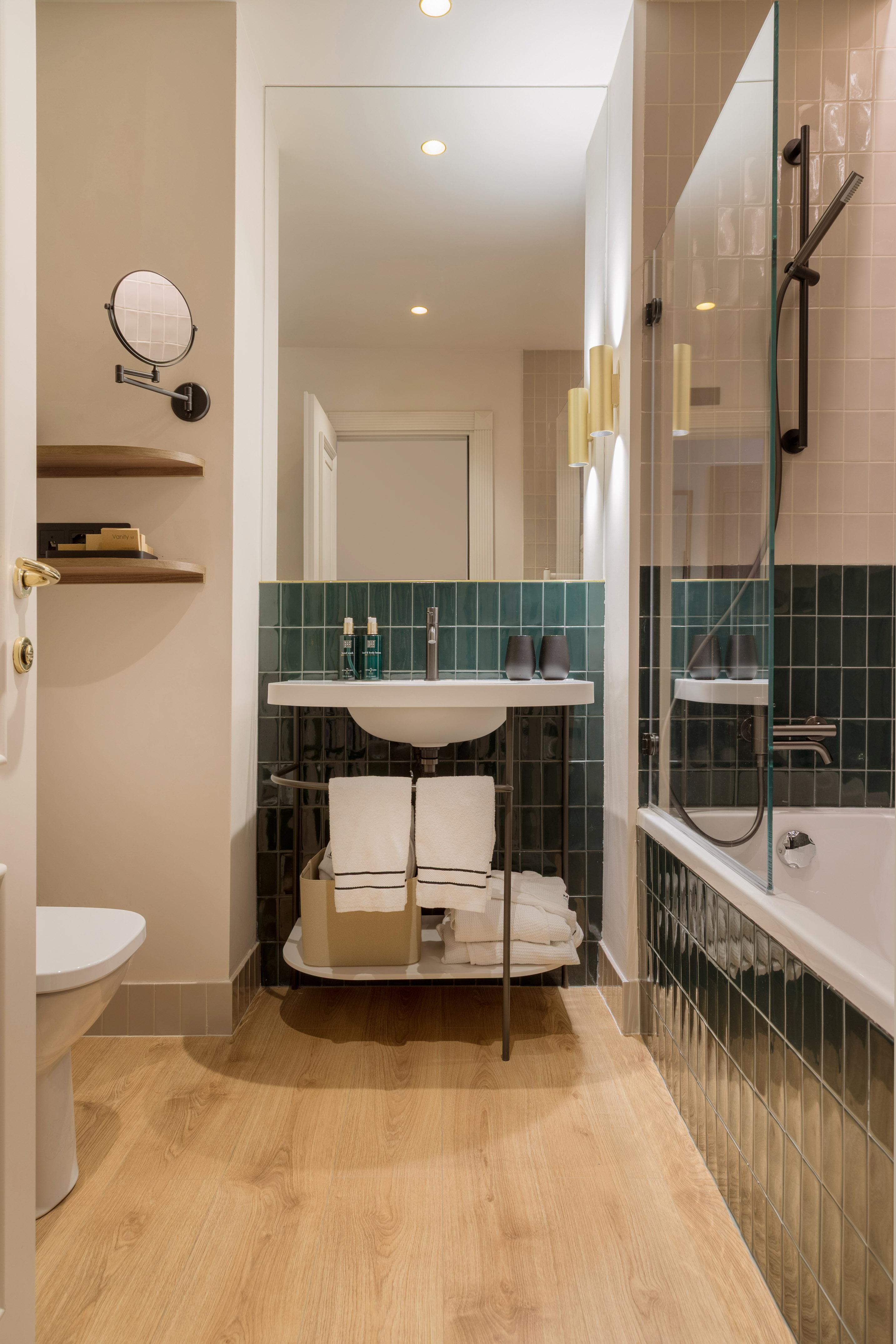Modern bathroom with dark green tiles, wood floor, floating vanity, shower, and bathtub.