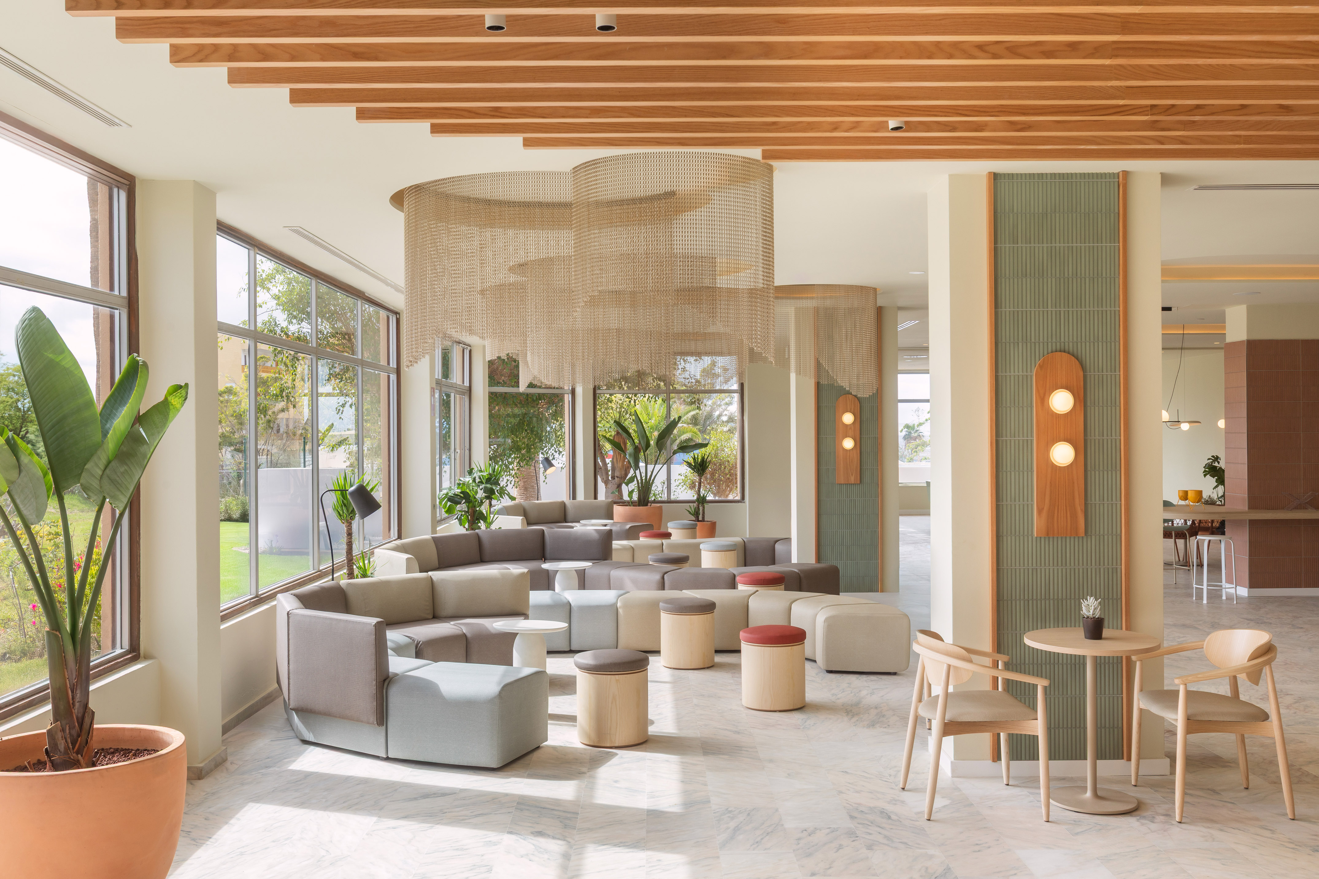 Modern hotel lobby with modular seating, chain mesh decor, and large windows.