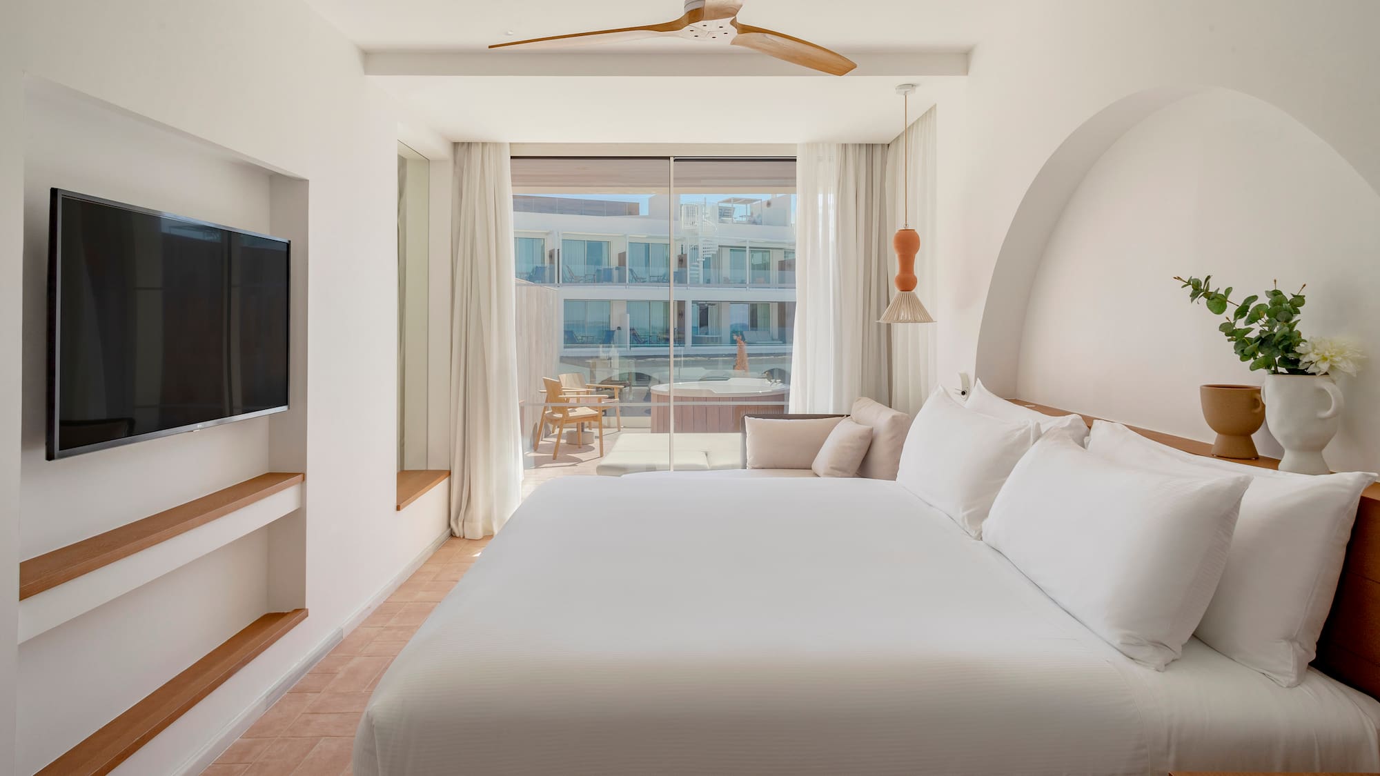 a bed in a room with a television and a ceiling fan