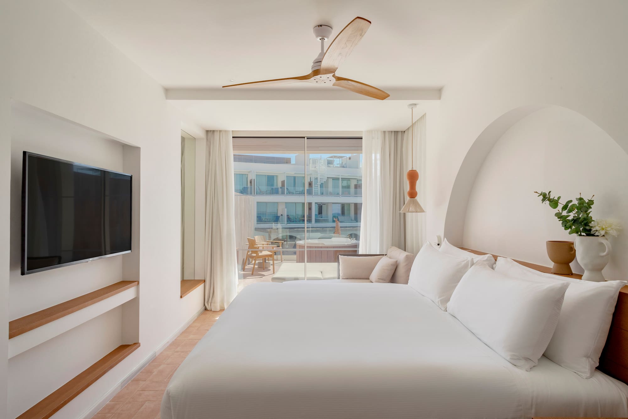 a bed in a room with a television and a ceiling fan