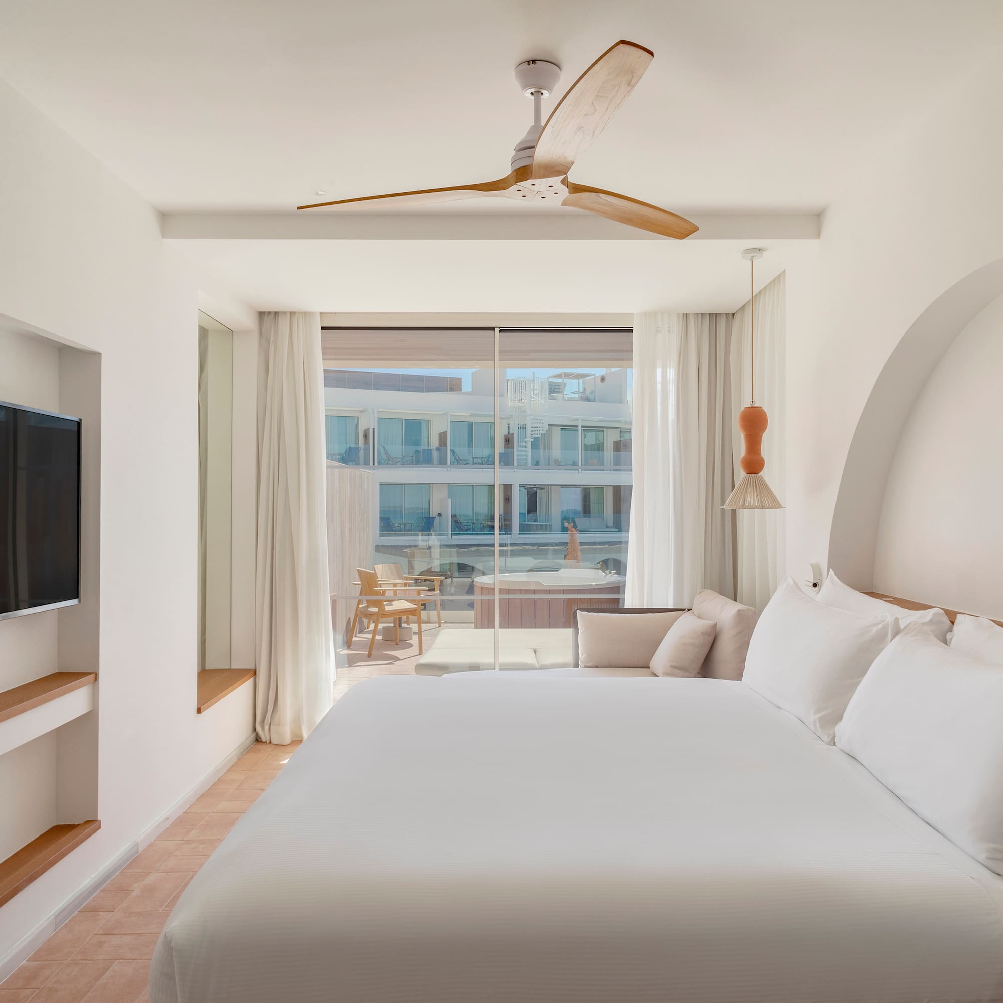a bed in a room with a television and a ceiling fan