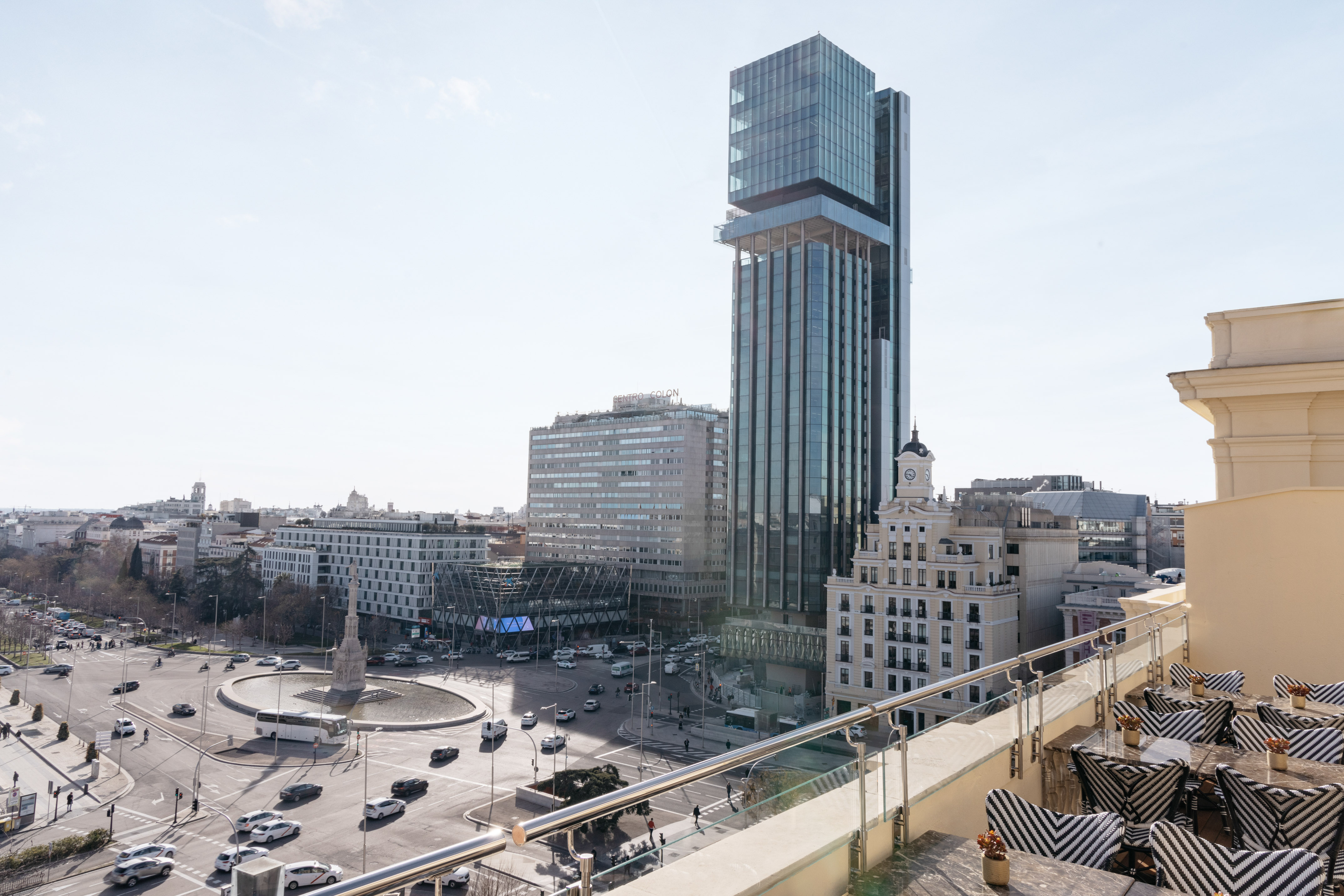 Madrid city view from rooftop terrace: modern skyscraper, Plaza de Colón, traffic.