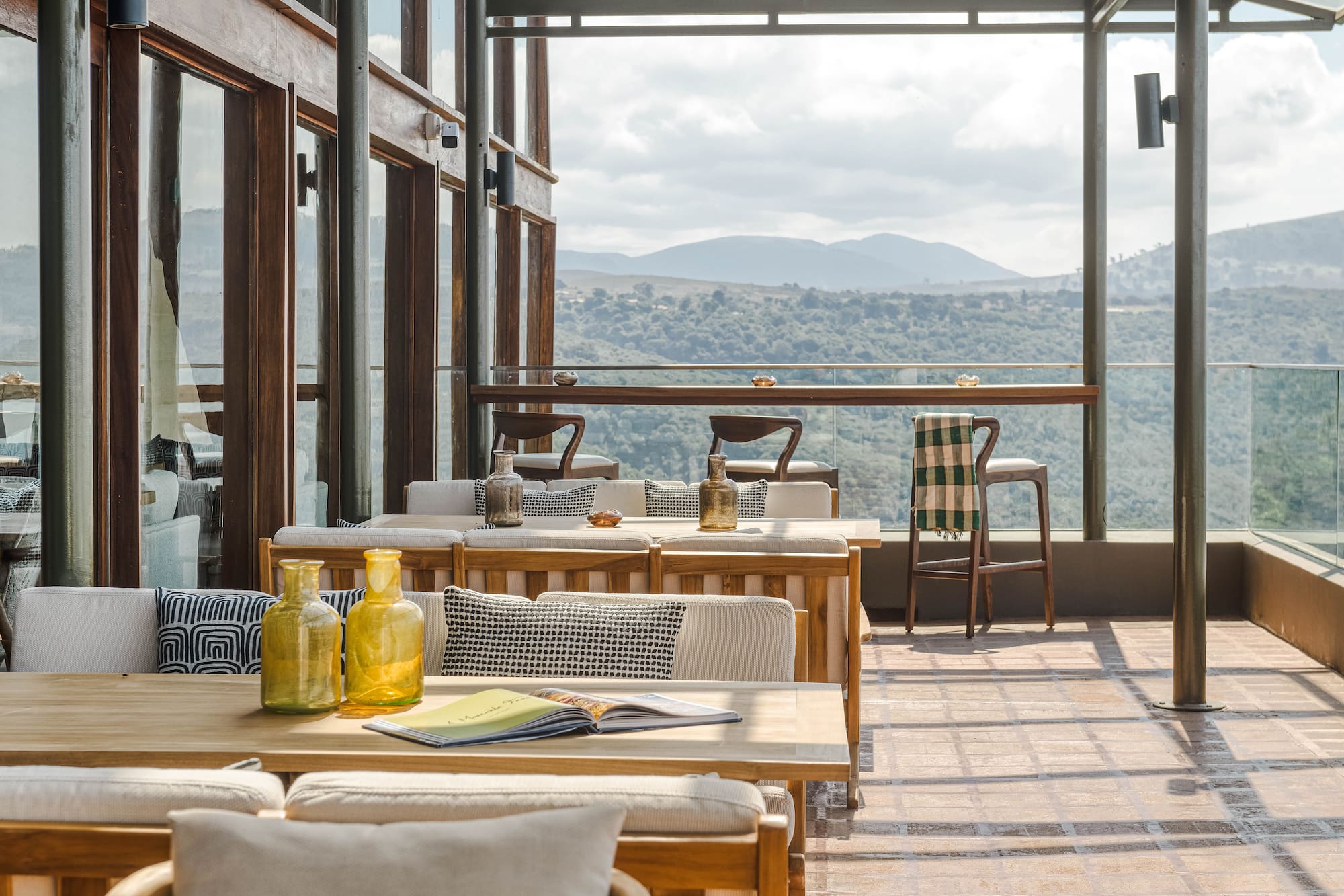 Outdoor dining terrace with mountain view, wooden tables, and modern design.