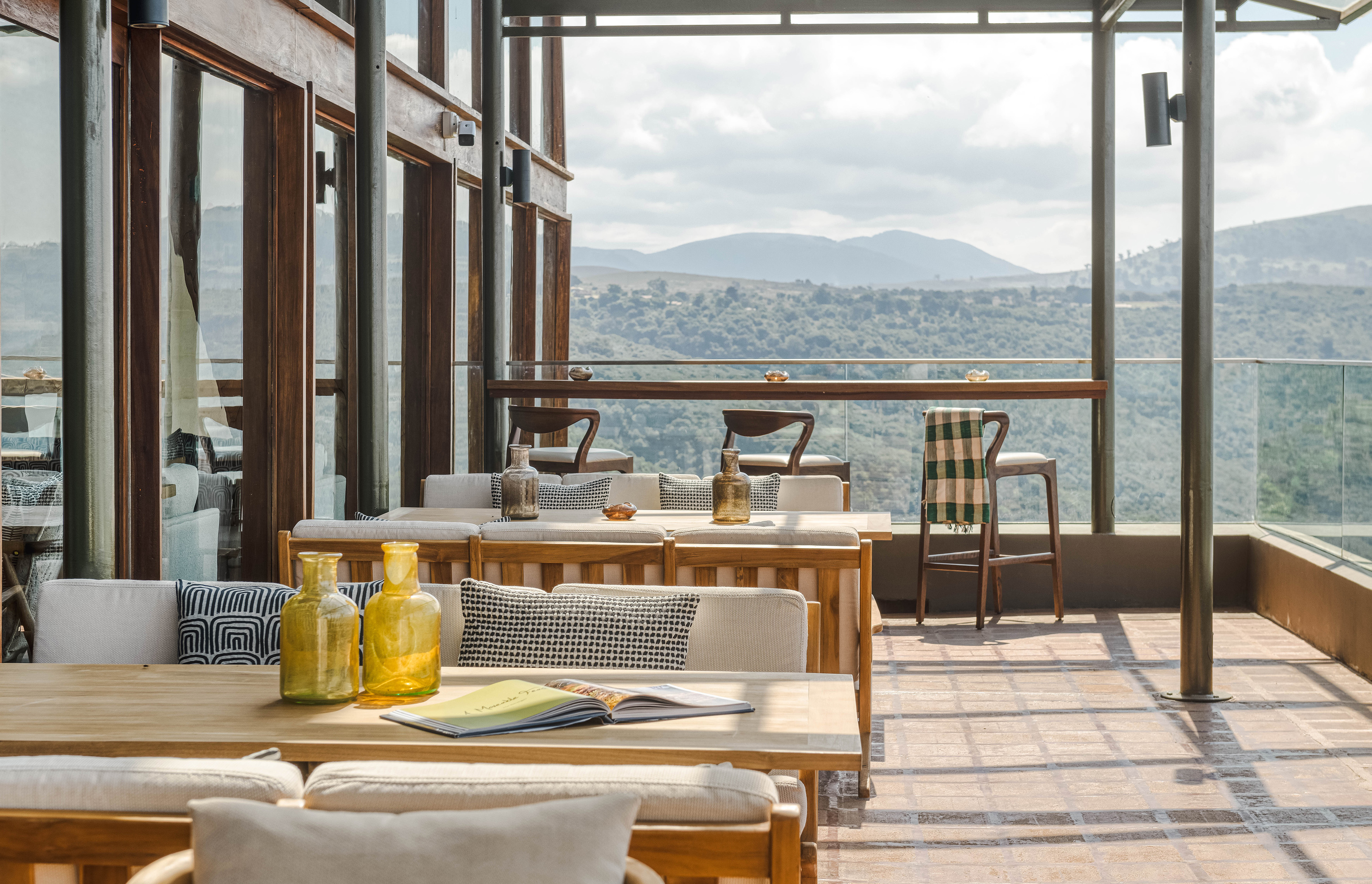 Outdoor dining terrace with mountain view, wooden tables, and modern design.