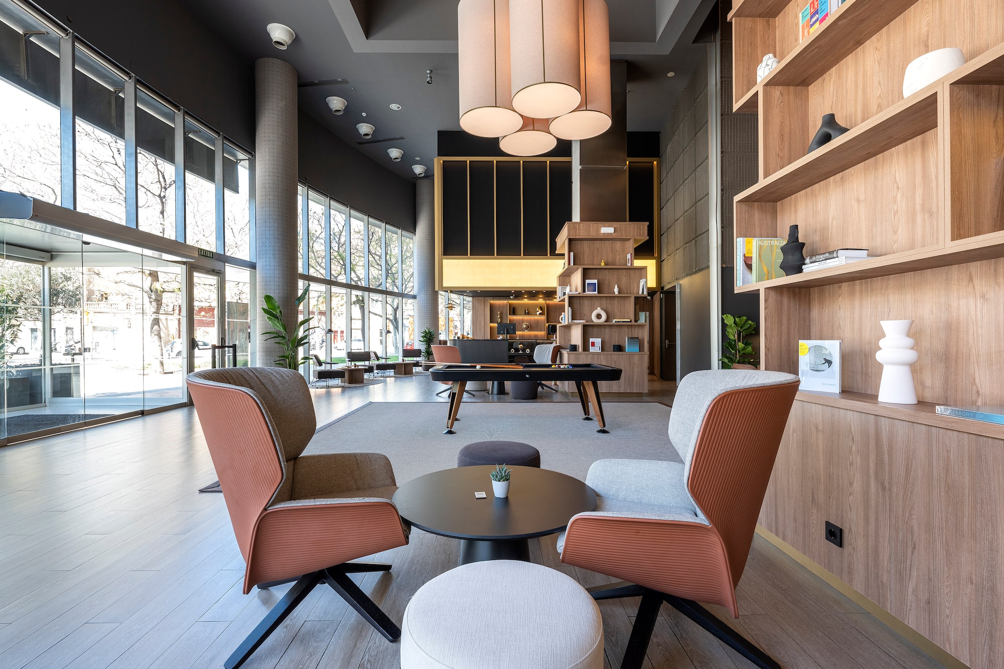 Modern hotel lobby lounge with stylish armchairs, coffee table, and wood shelves.