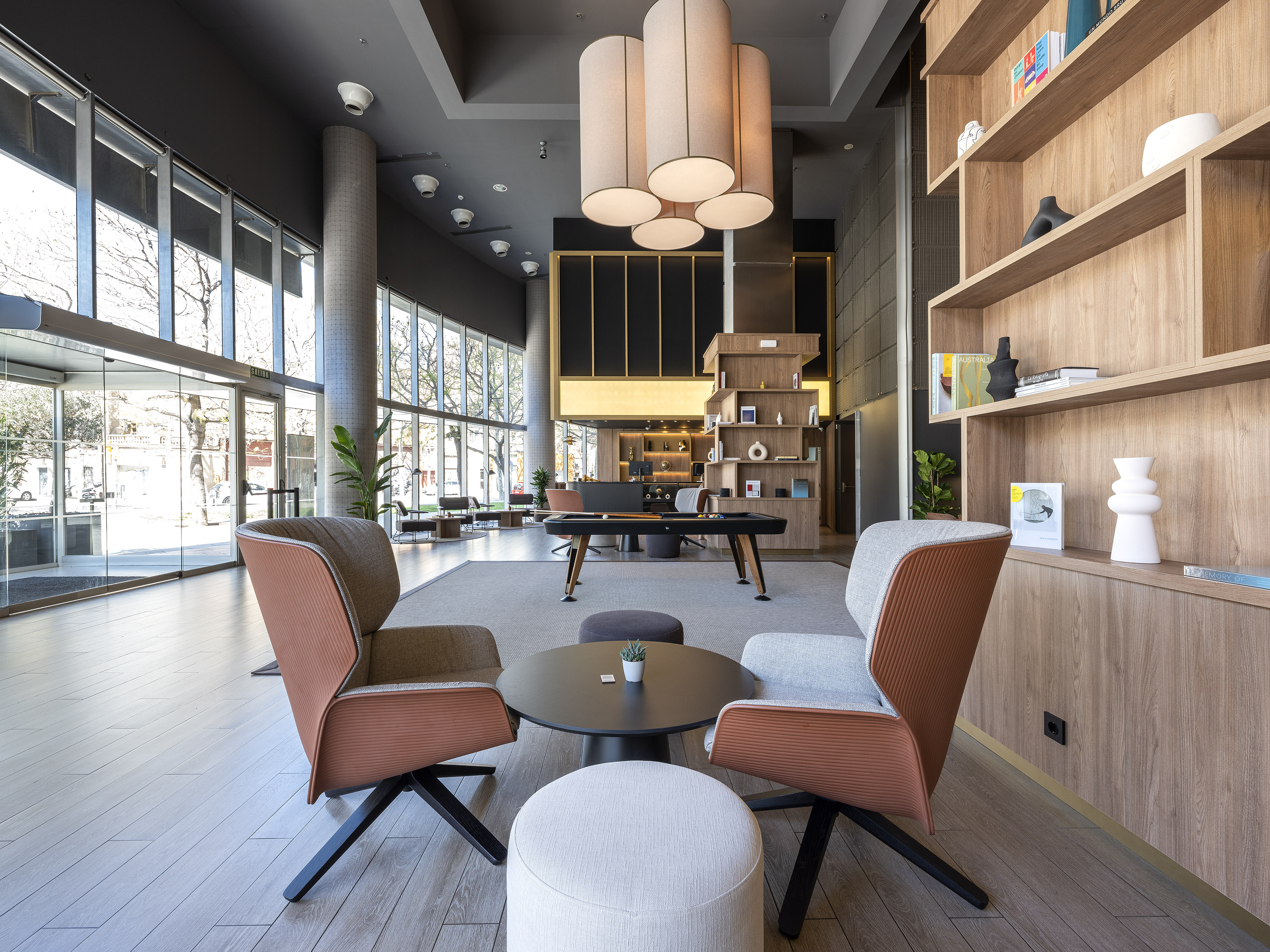 Modern hotel lobby lounge with stylish armchairs, coffee table, and wood shelves.