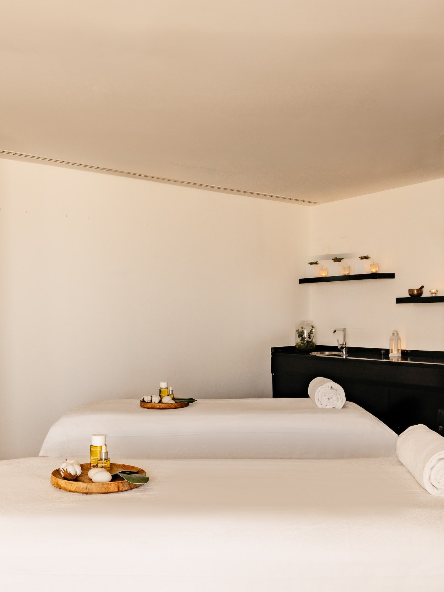 Dos camillas de masaje con aceites y toallas en sala de spa moderna.