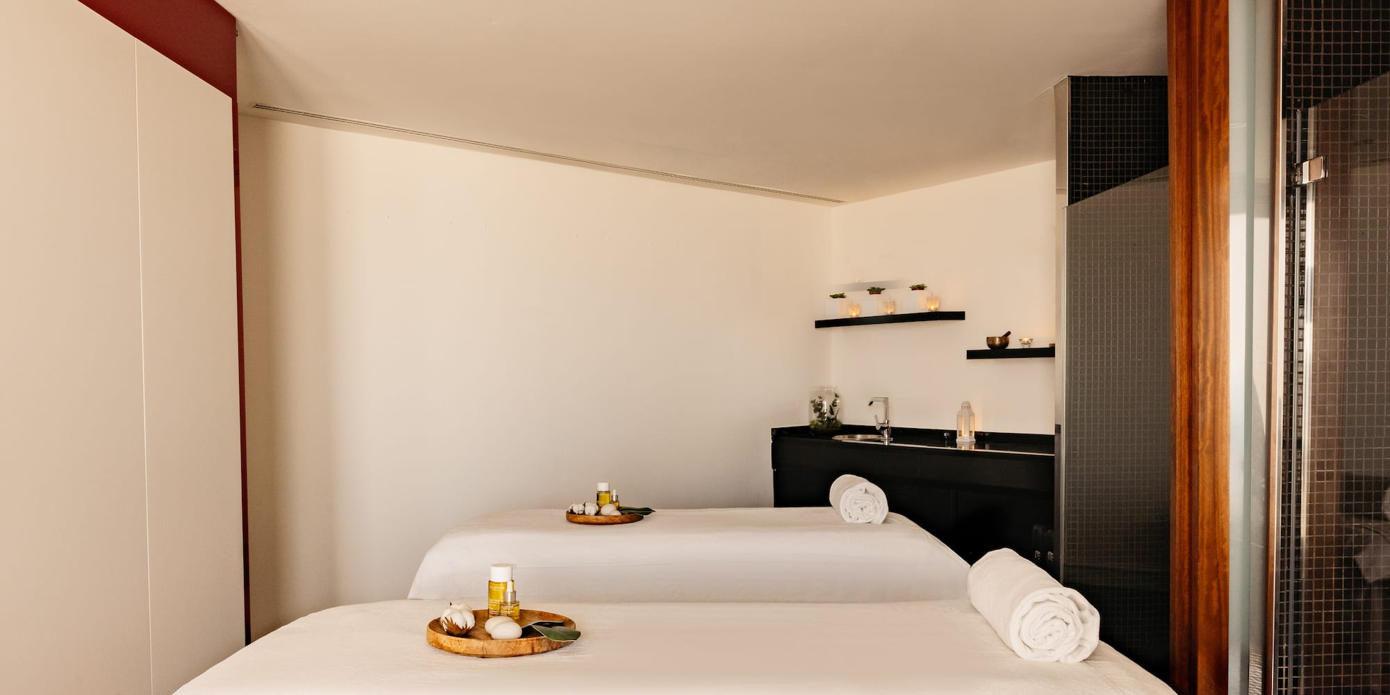 Luxury spa room with two massage tables, aromatherapy oils, and towels.