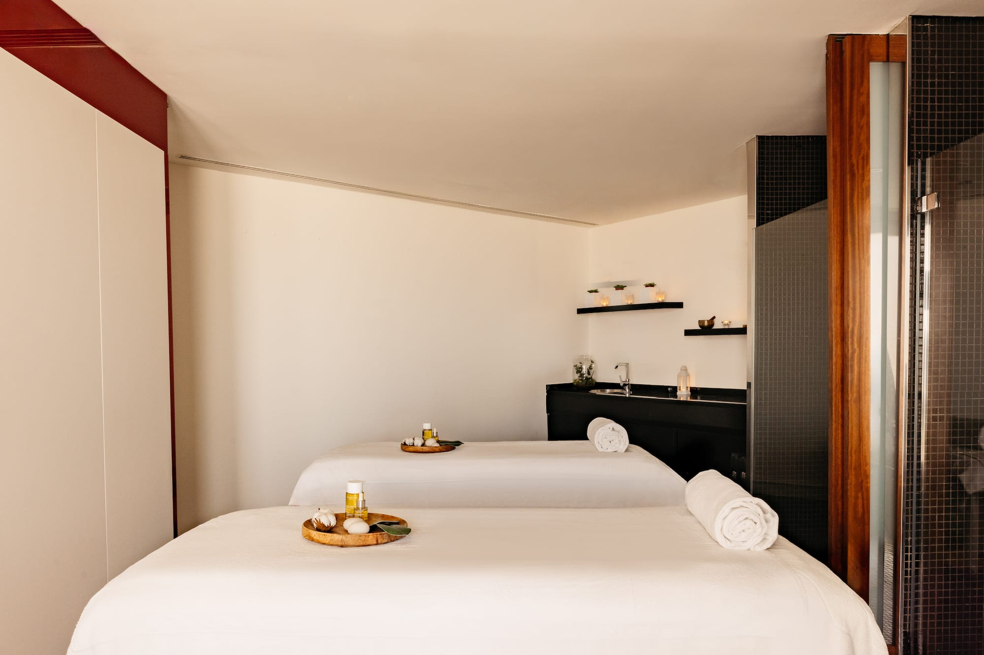 Sala de spa moderna con dos camillas de masaje y productos de relajación.