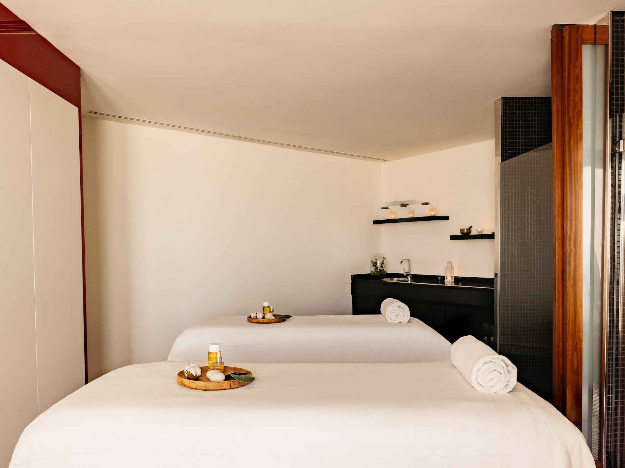 Sala de spa moderna con dos camillas de masaje y productos de relajación.