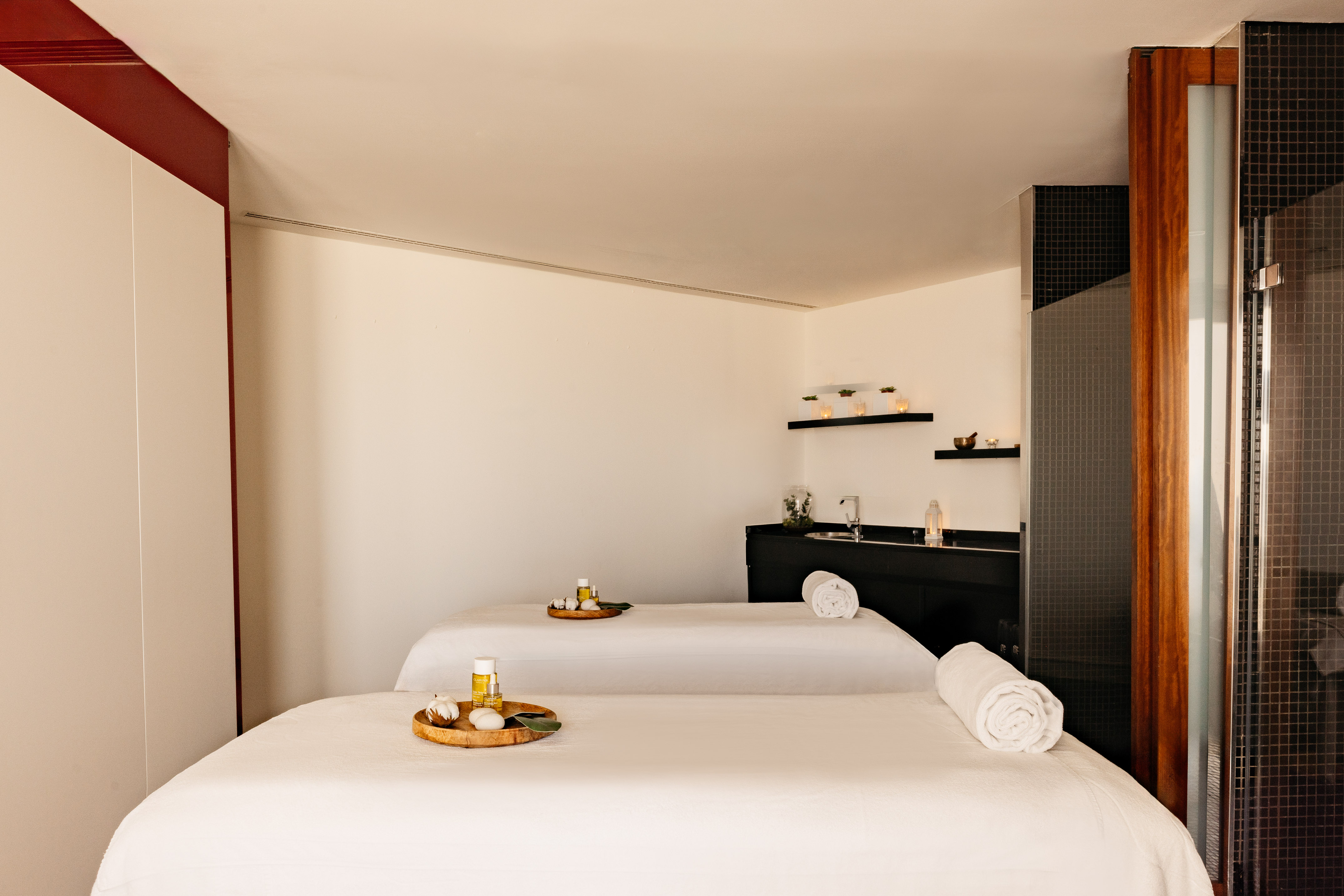 Dos camillas de masaje con aceites y toallas en sala de spa moderna.