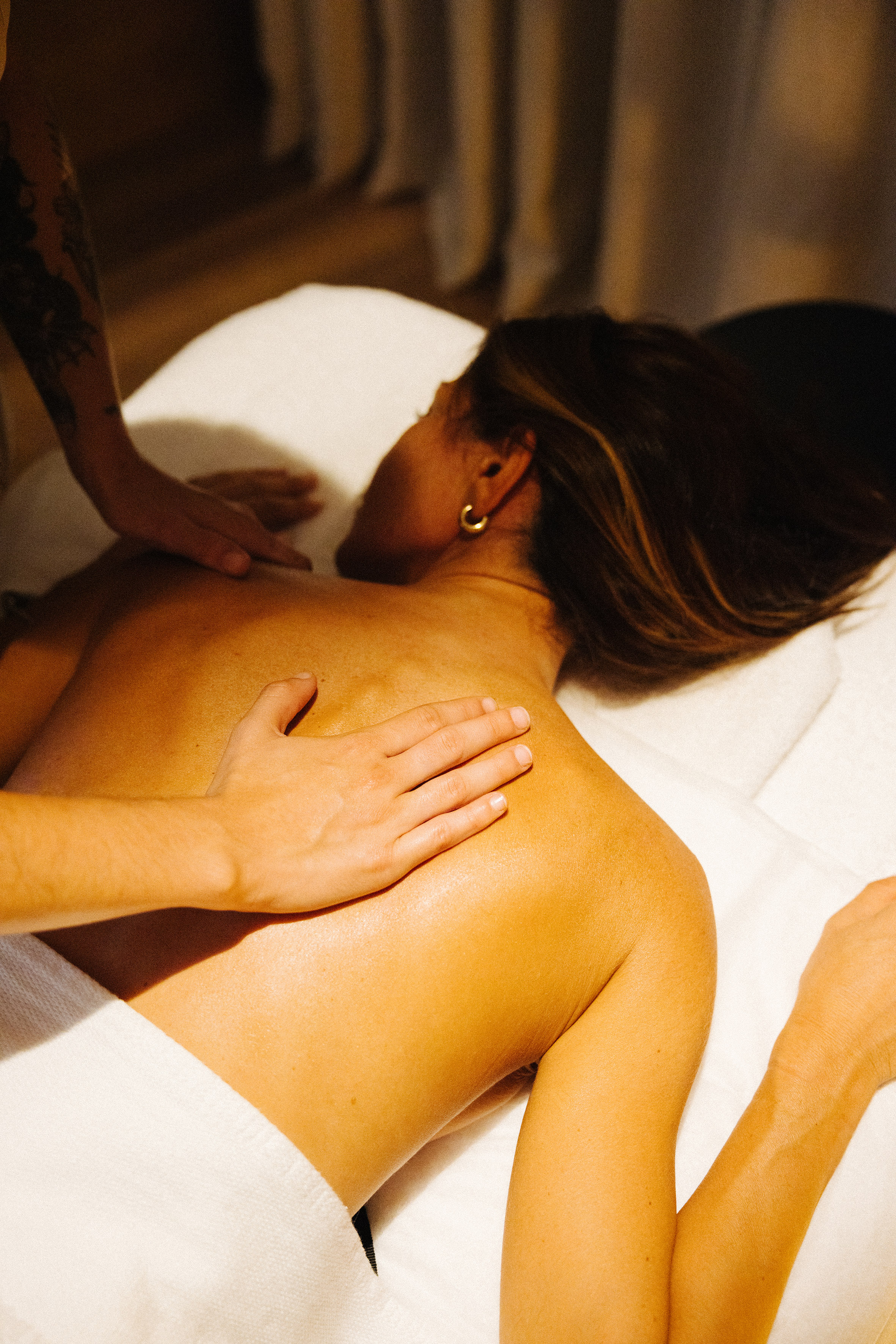 Hands massaging a woman's back with oil at a serene spa.