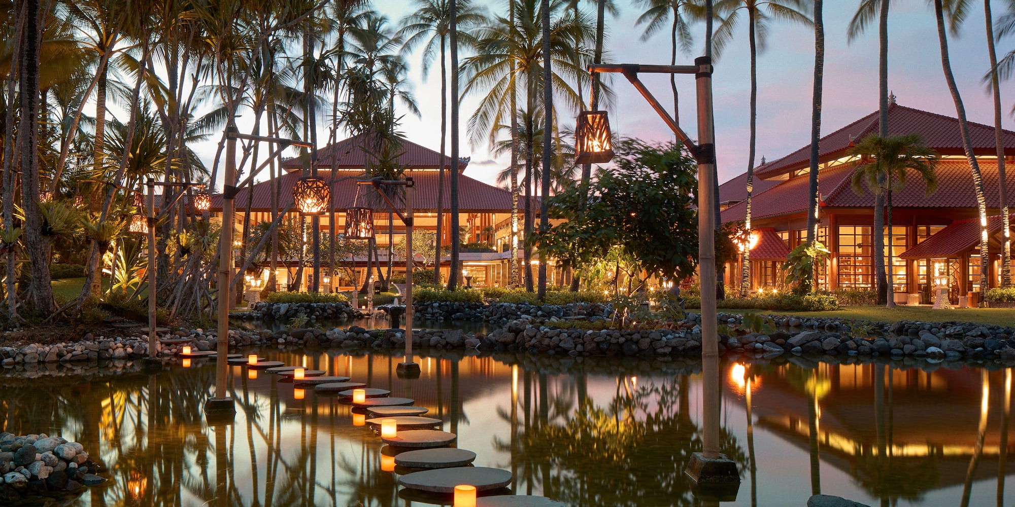 a walkways leading to a pond with palm trees