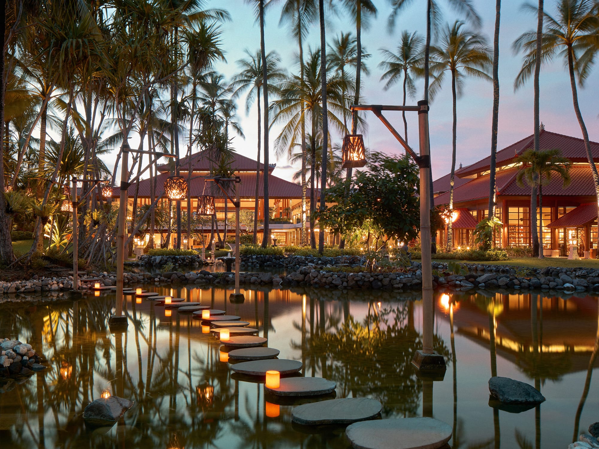 a walkways leading to a pond with palm trees