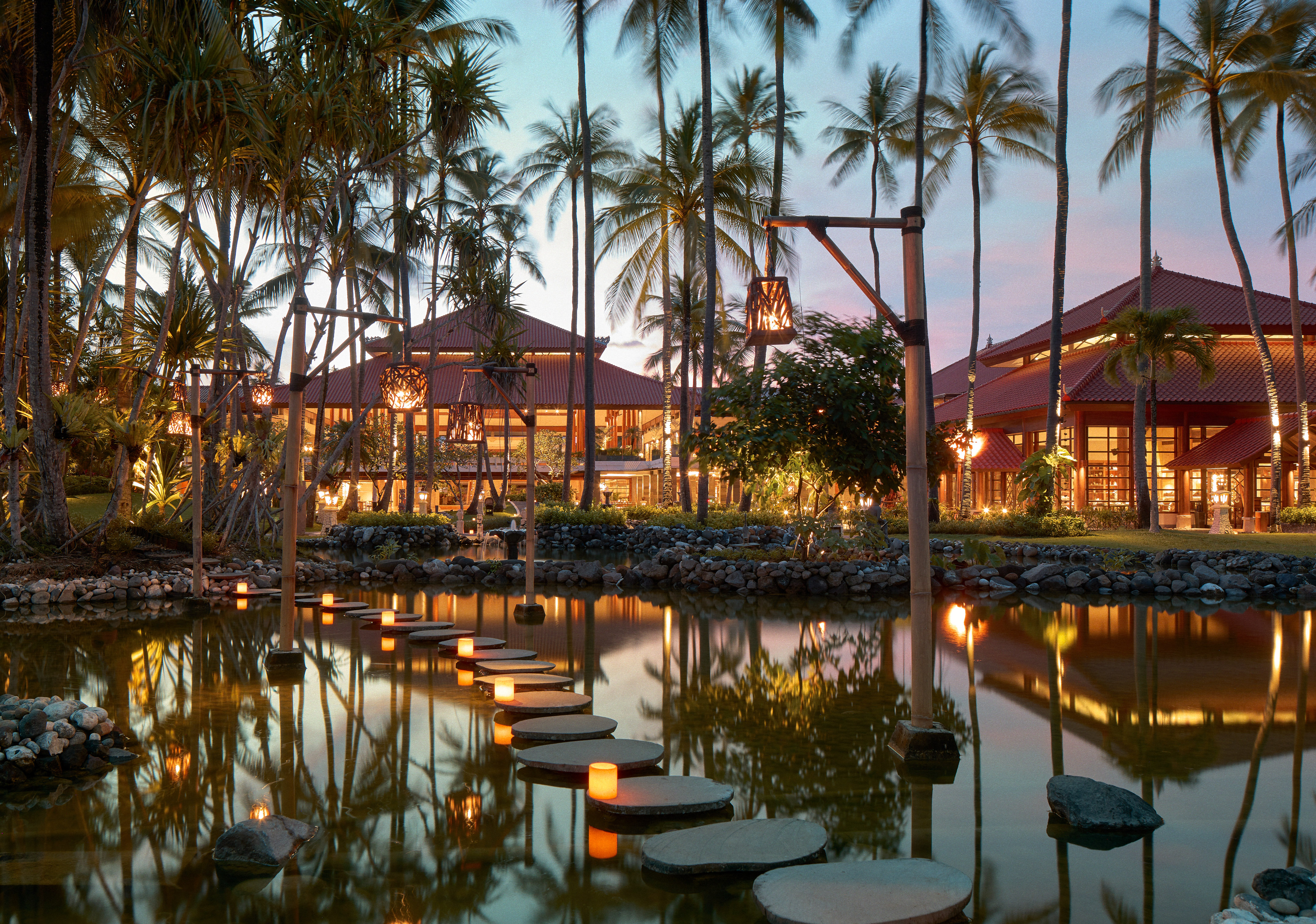a walkways leading to a pond with palm trees
