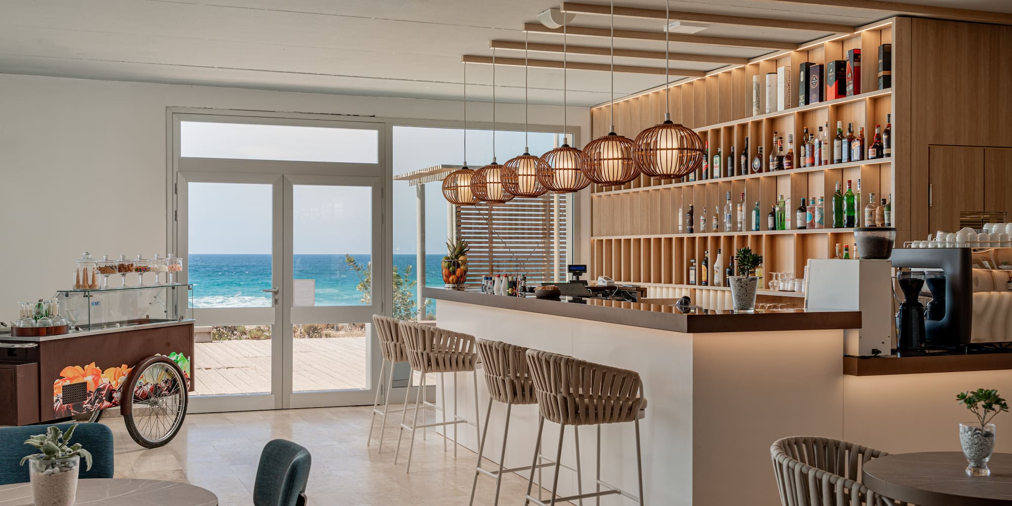 a bar with chairs and a shelf with bottles on it