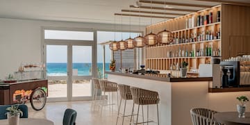 a bar with chairs and a shelf with bottles on it