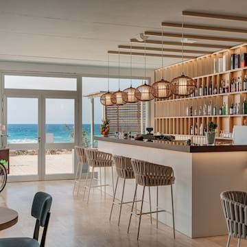 a bar with chairs and a shelf with bottles on it