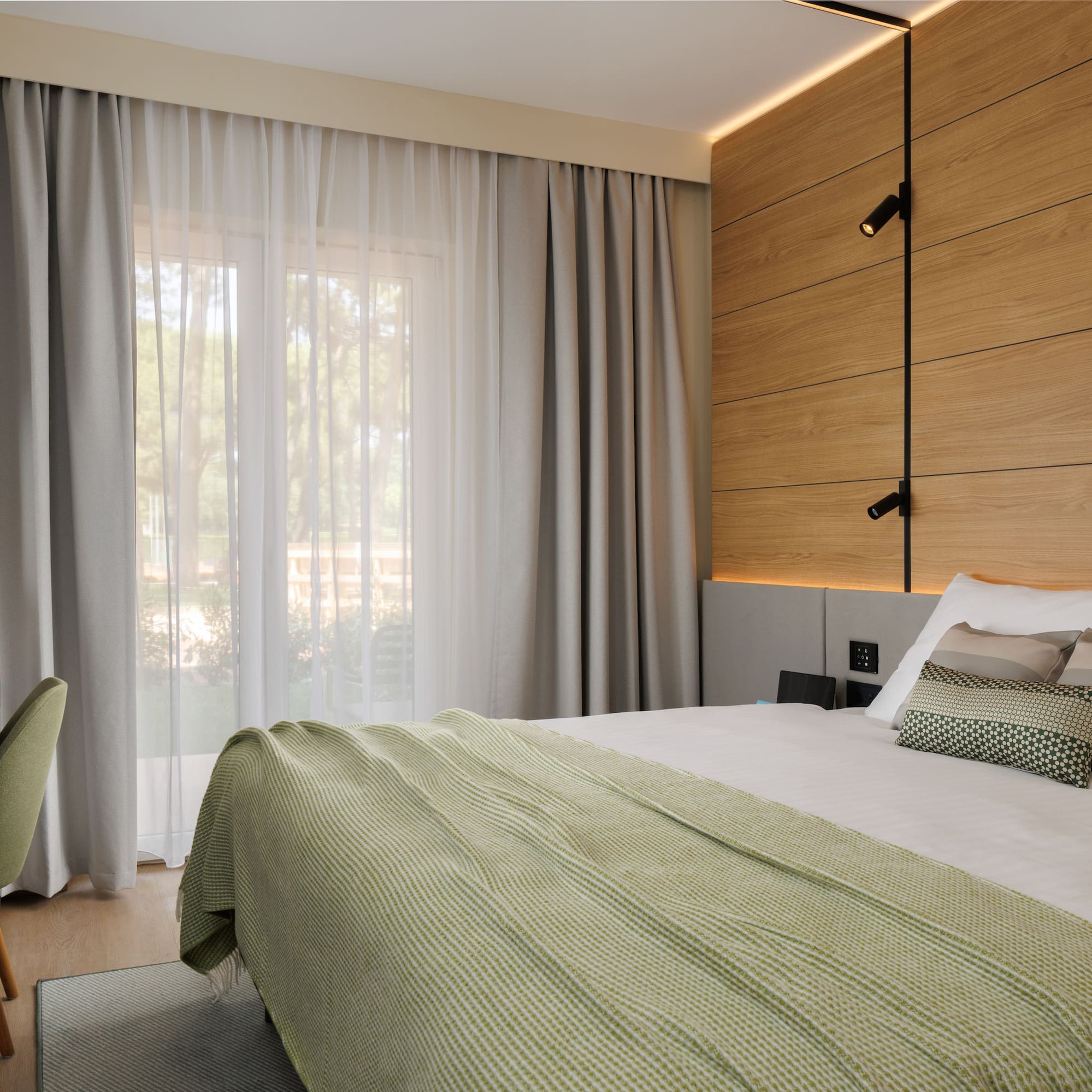 a bed with a green blanket and a wood paneled wall