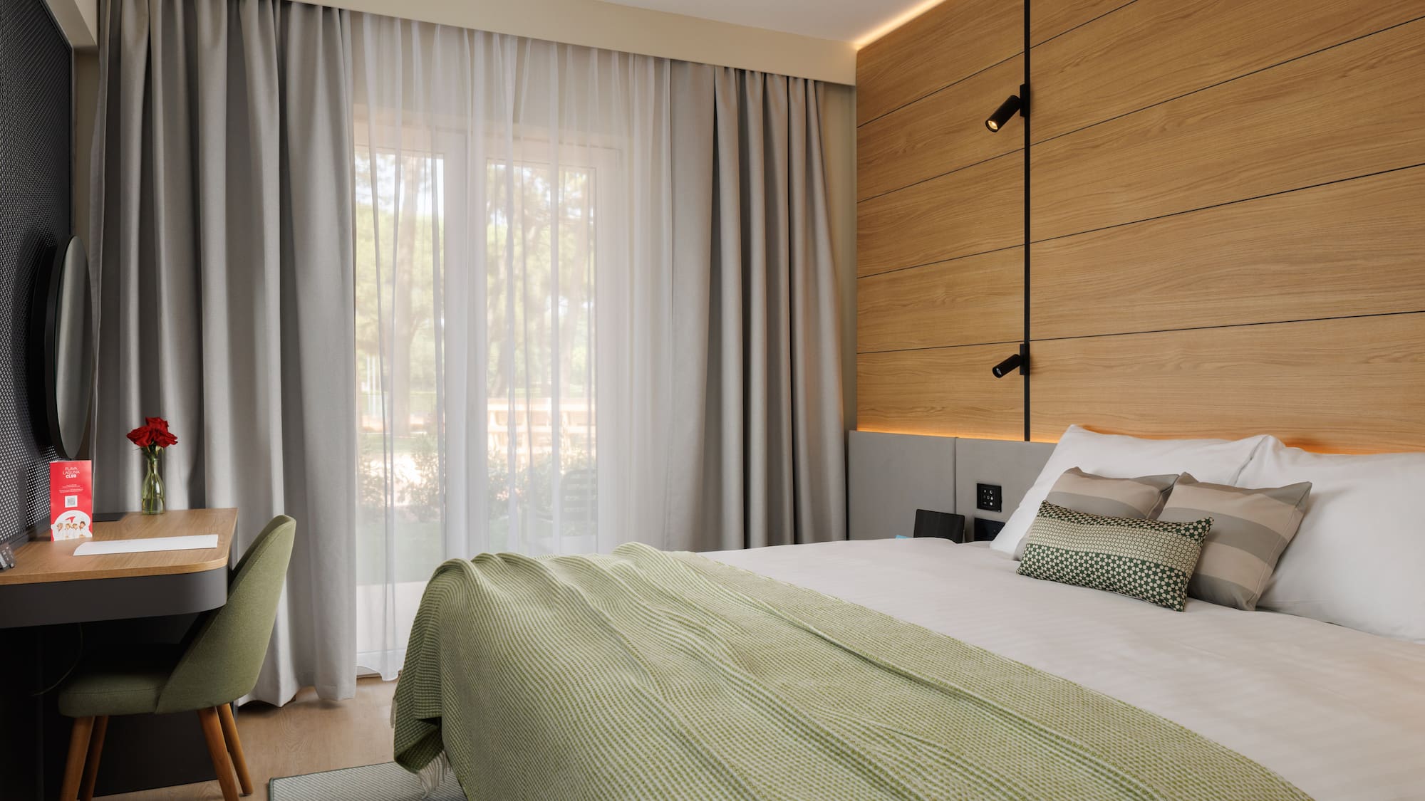 a bed with a green blanket and a wood paneled wall