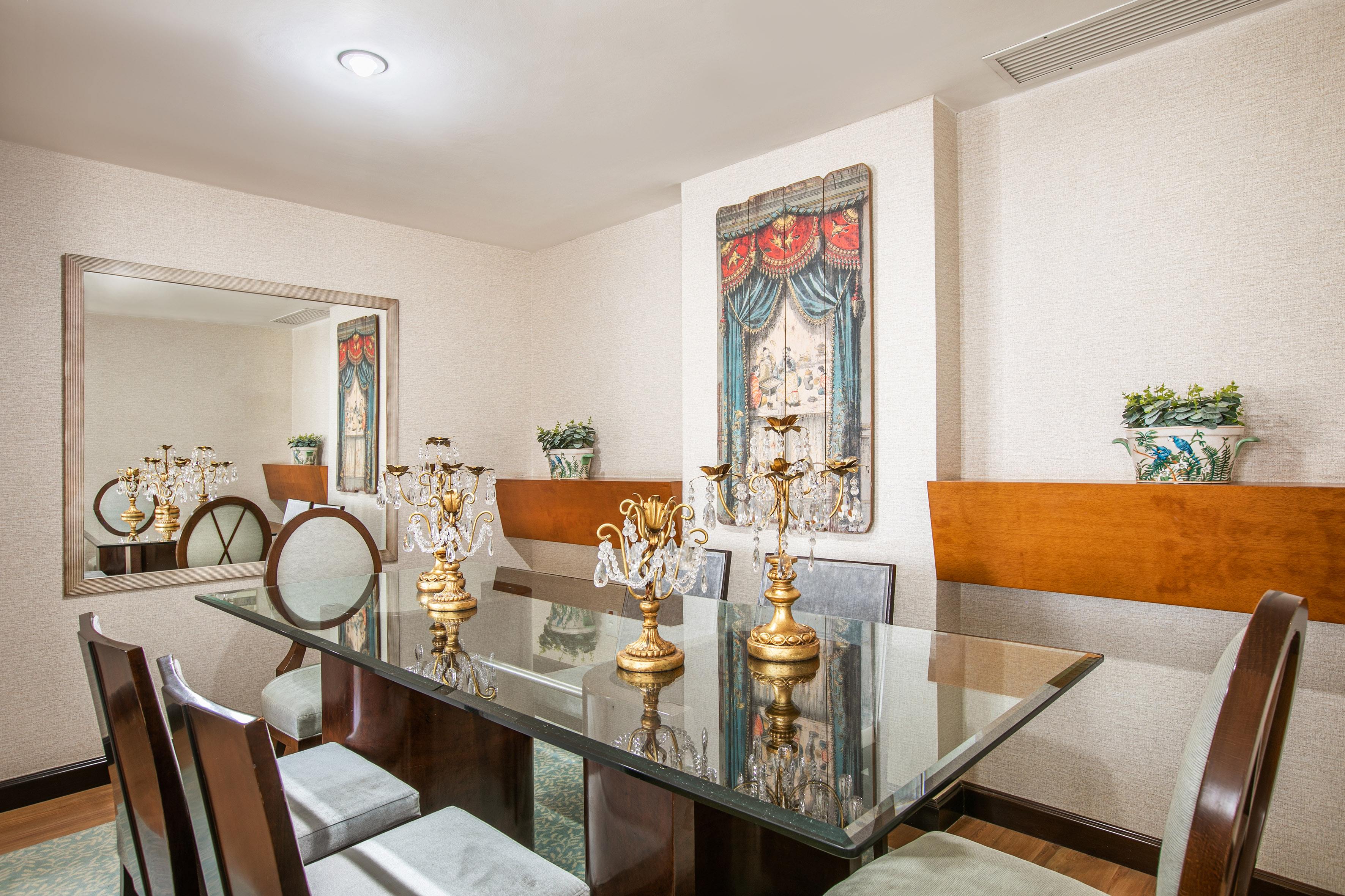 Elegant dining room with glass table, crystal candelabras, and unique wall art.