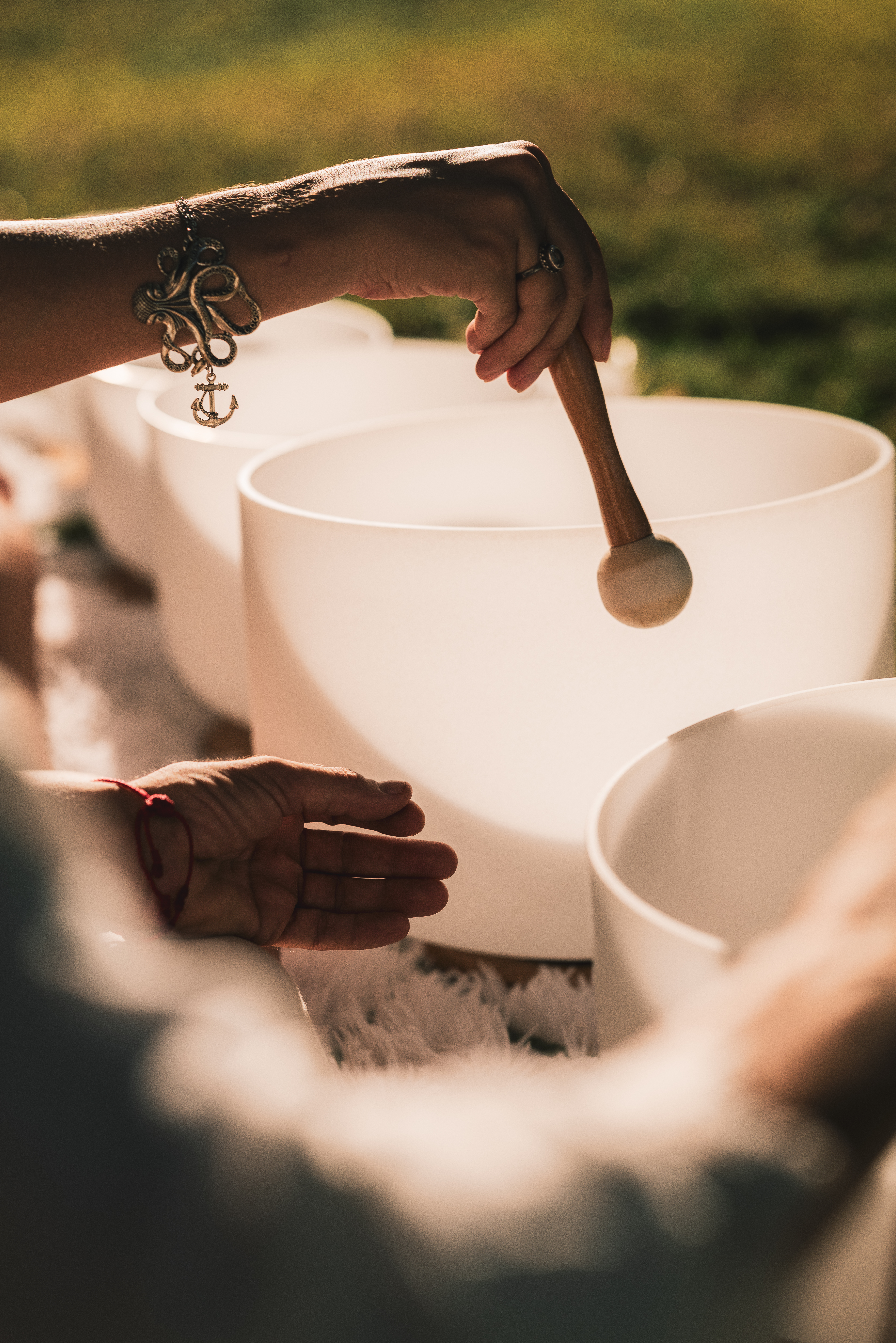 Hand striking crystal singing bowl with mallet for sound healing meditation.