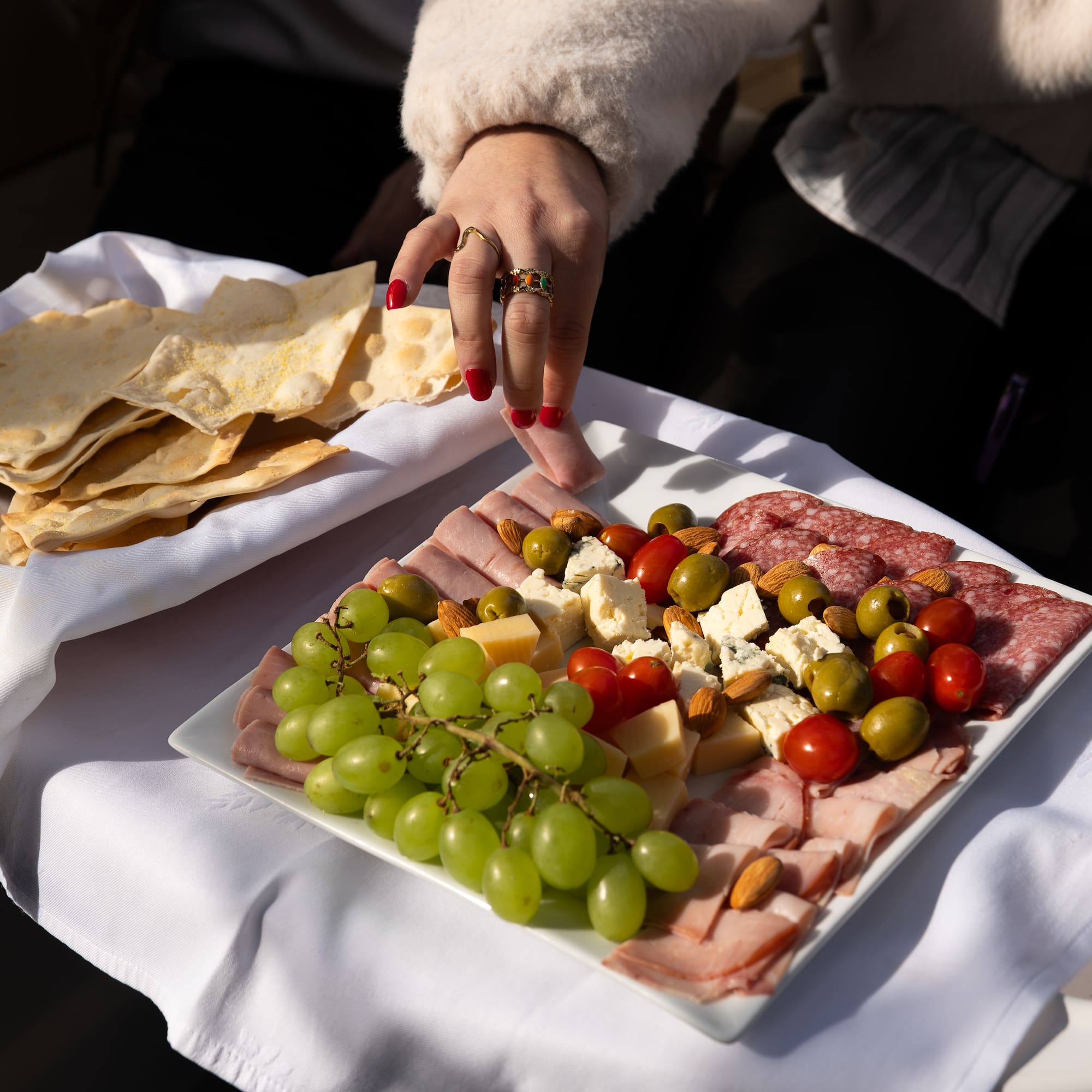 a person's hand reaching for a plate of food