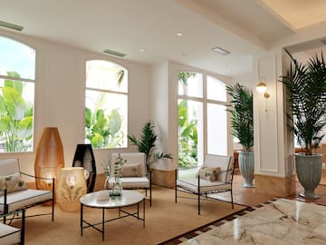 a room with white walls and white walls and a white floor with white chairs and a table with plants
