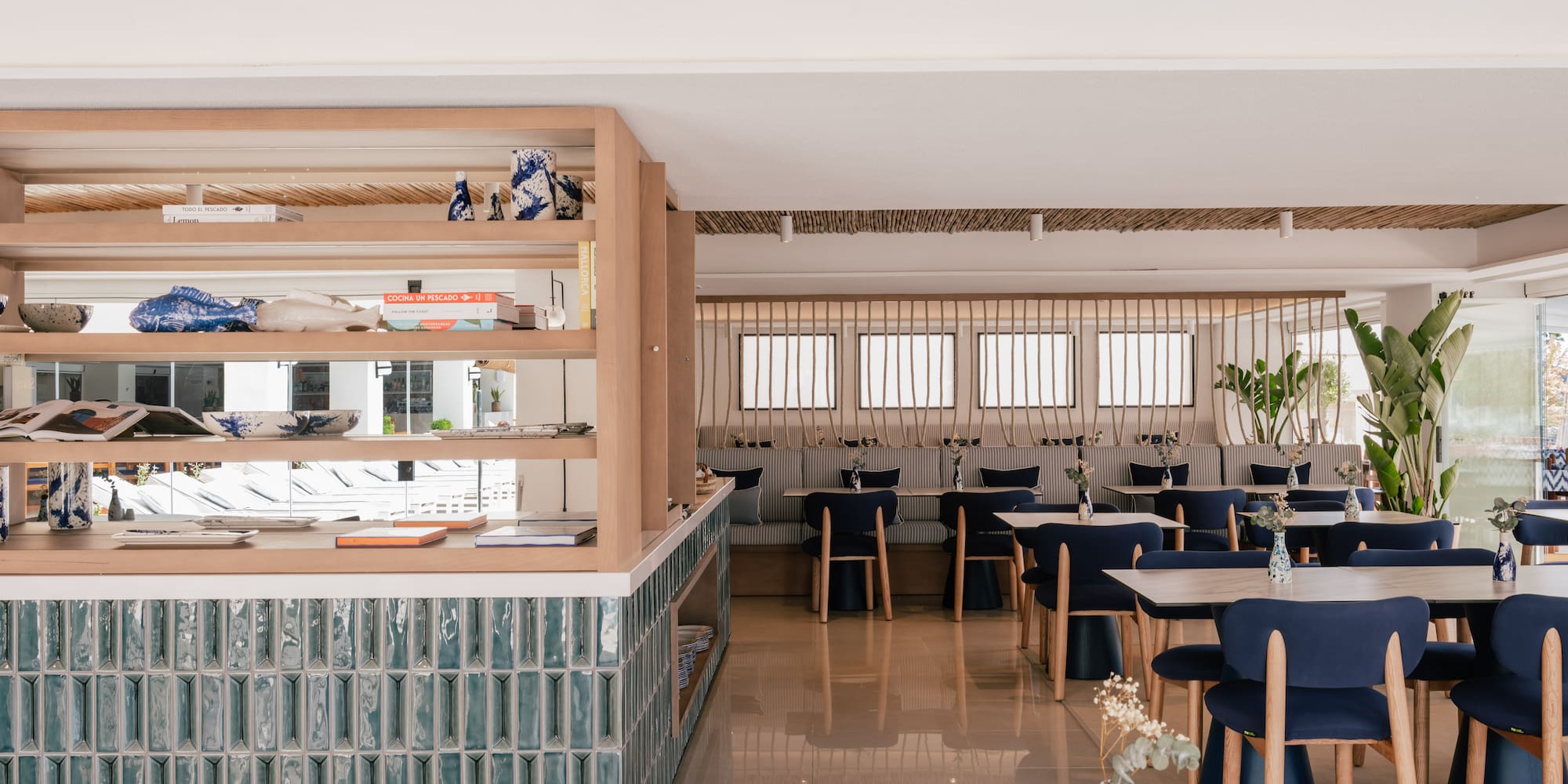 Coastal restaurant with bamboo ceiling, blue chairs, and teal counter.