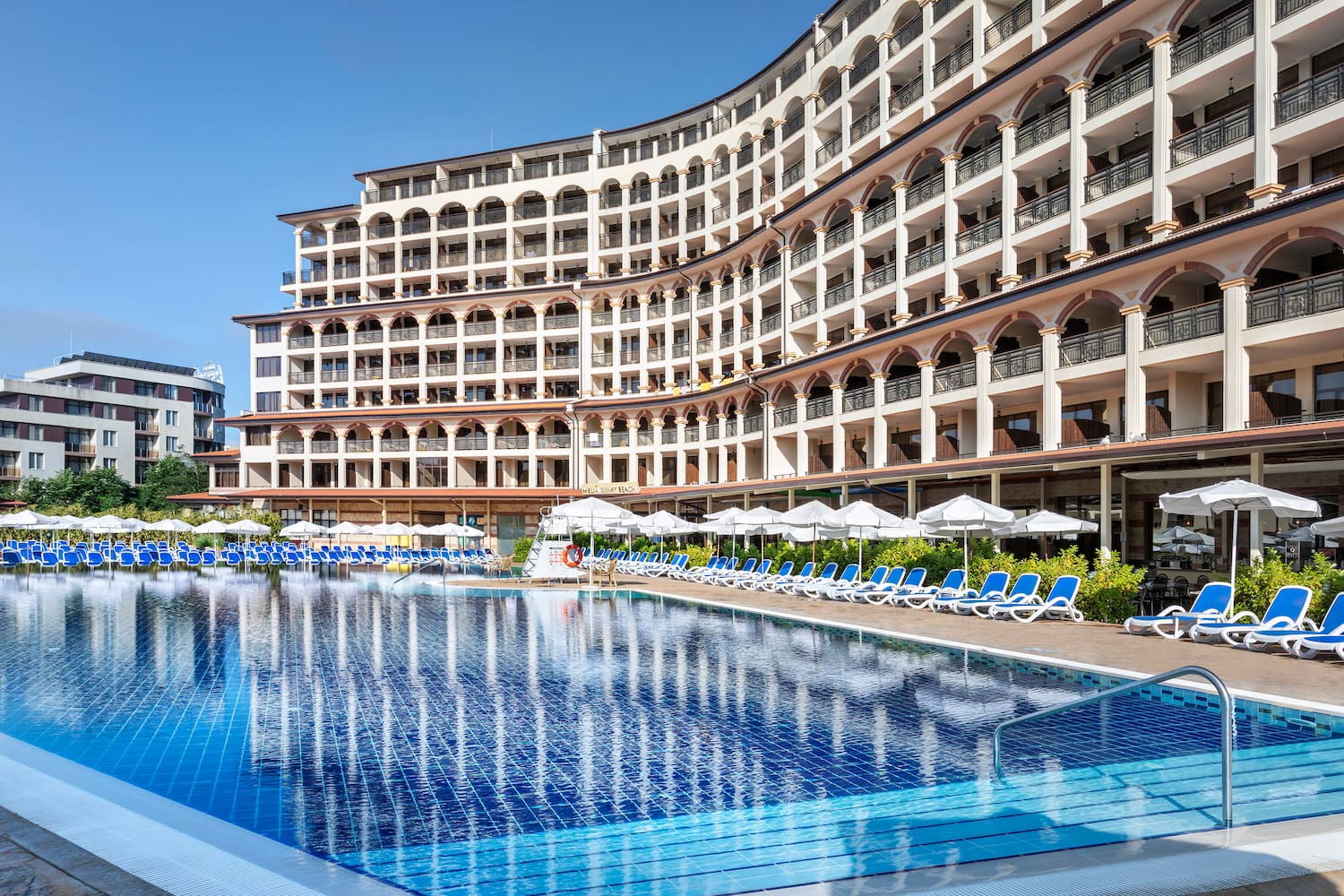 a pool with umbrellas and chairs in front of a building