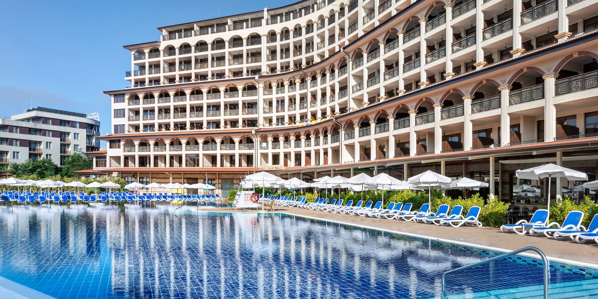 a pool with umbrellas and chairs in front of a building