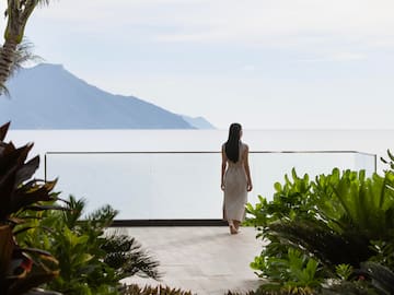 a woman walking on a deck overlooking a body of water