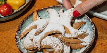a person's hand reaching for a plate of cookies