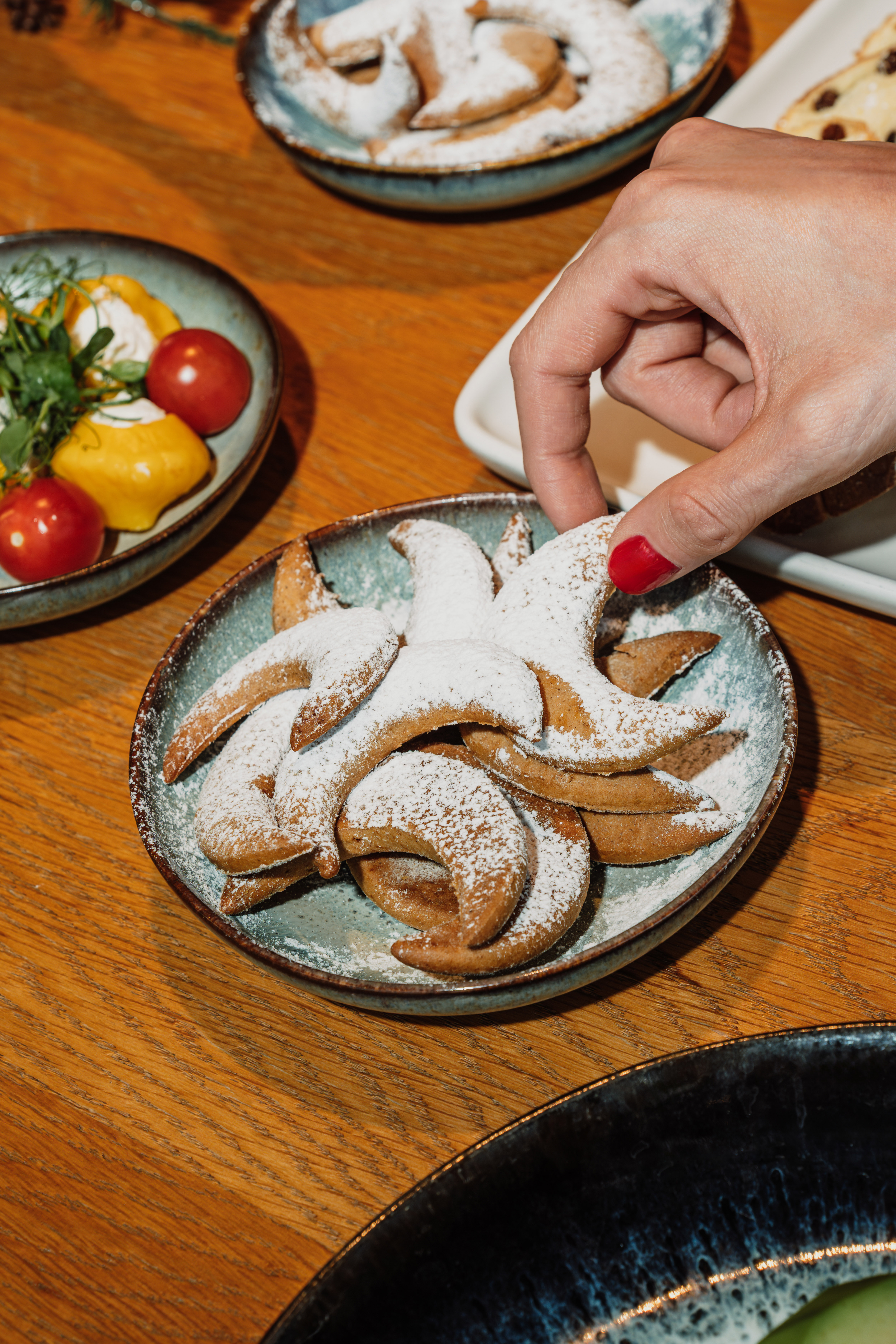 a person's hand reaching for a plate of cookies